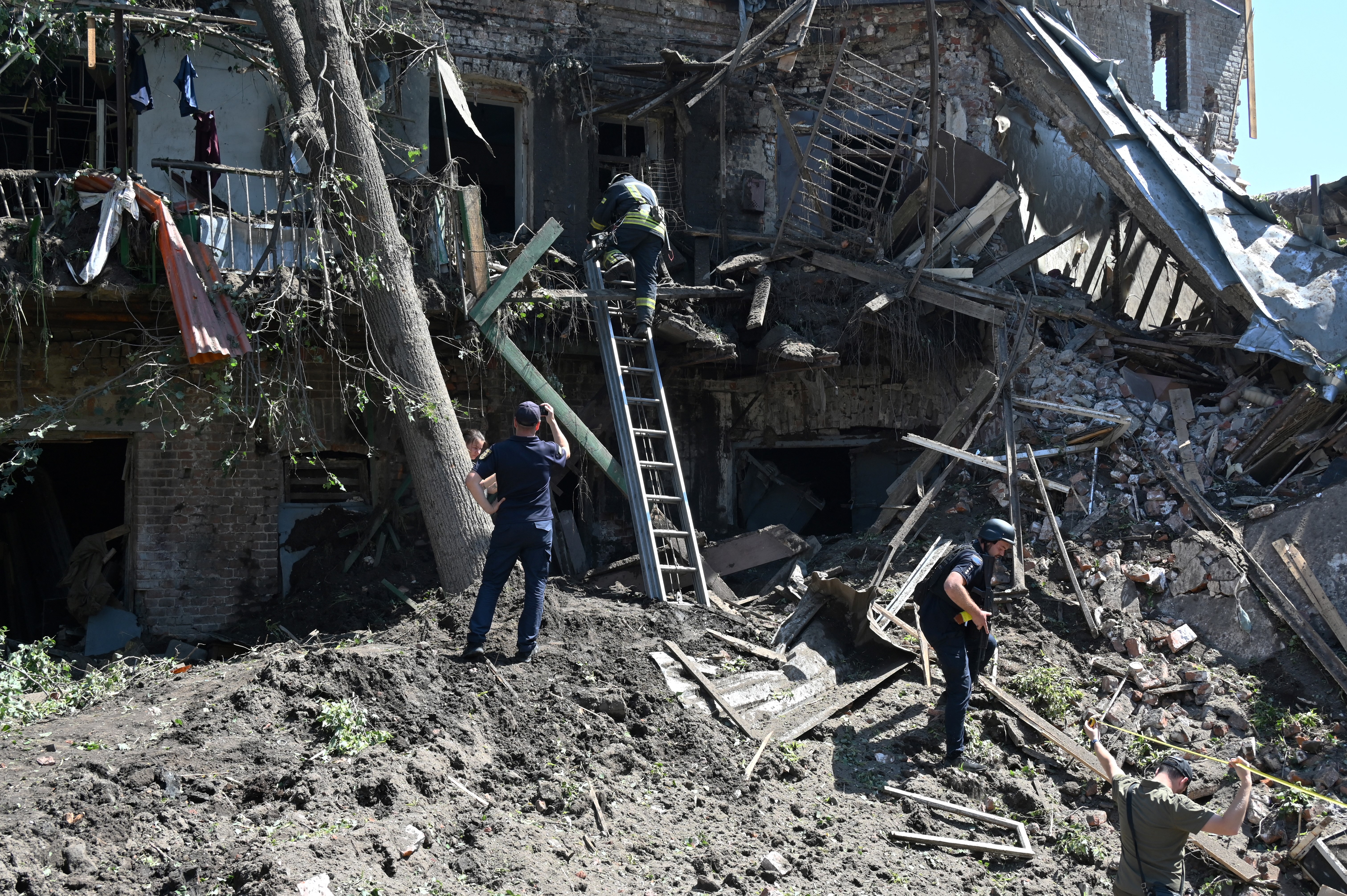 Ukrainian rescuers and security personnel work outside a residential buildings destroyed by a missile strike in Kharkiv, on July 9, 2022, amid Russia's military invasion launched on Ukraine.