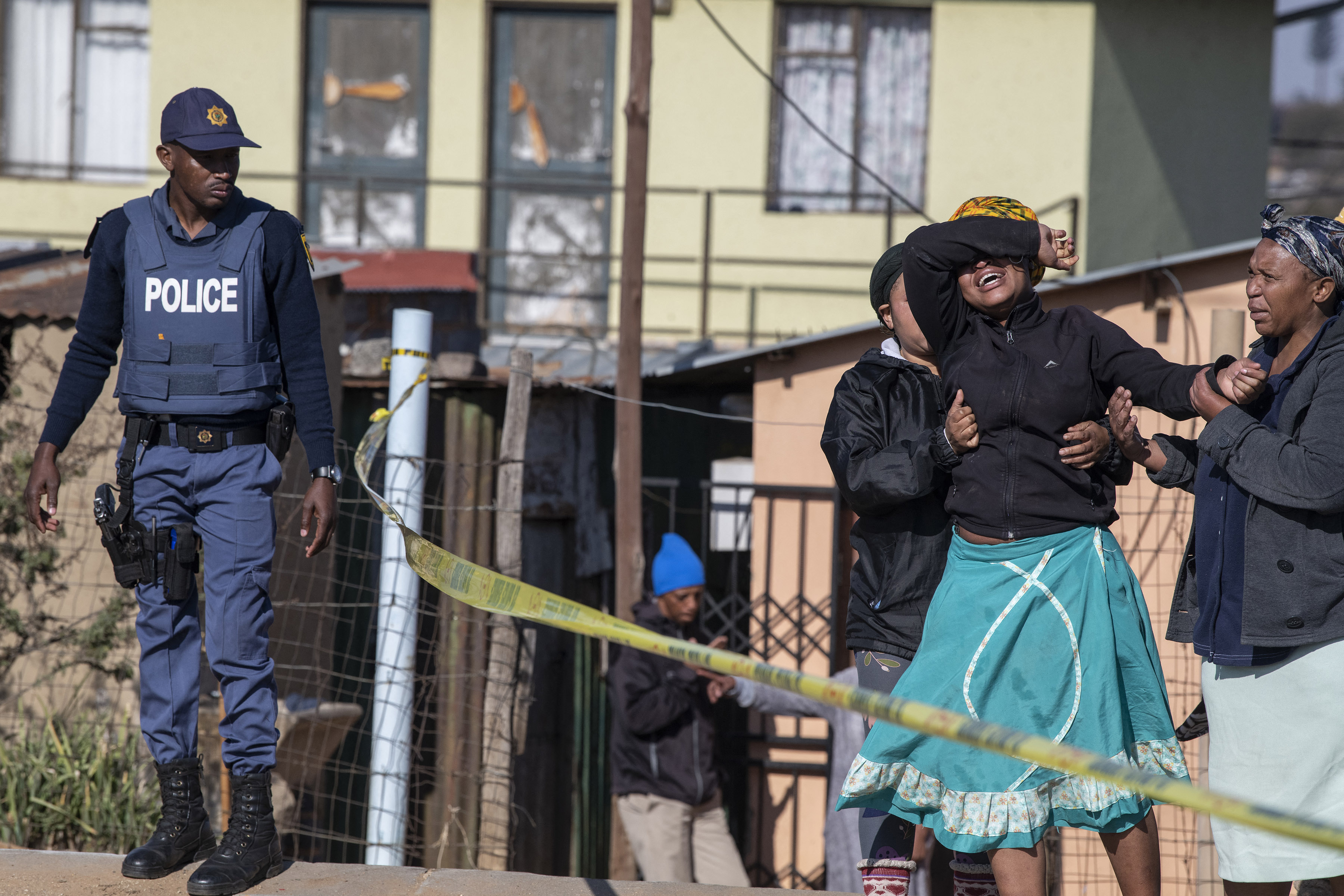 A relative of one of the victims cries as south African Police Service officers refuse to let her cross the police barrier and enter the crime scene in Soweto, South Africa,