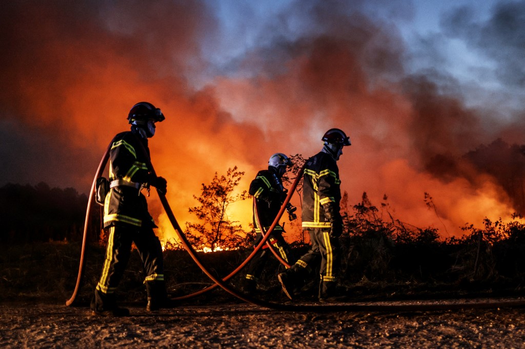 Firefighters try to control a forest fire in Louchats, south-western France