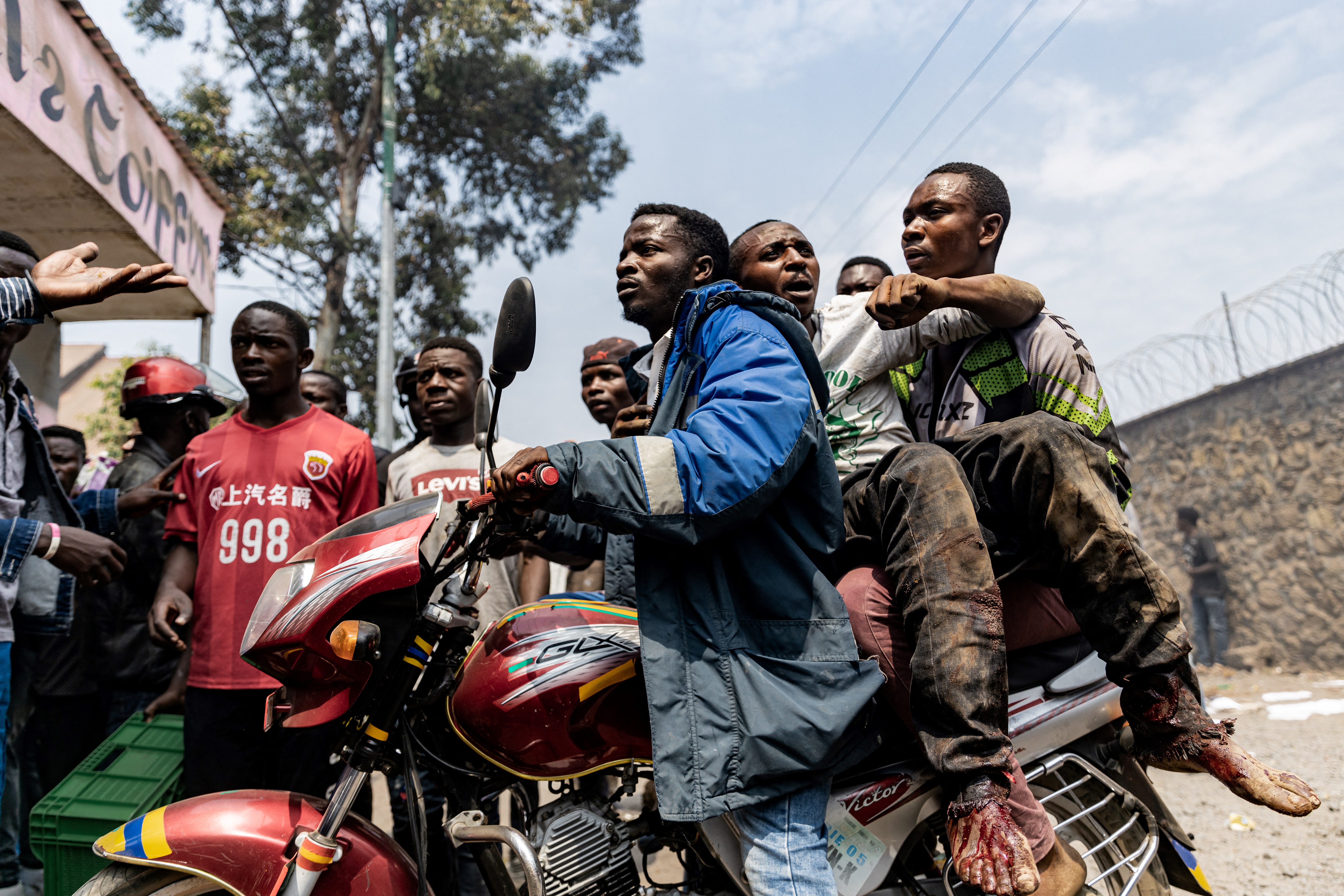 A wounded man is rushed away on a motorcycle