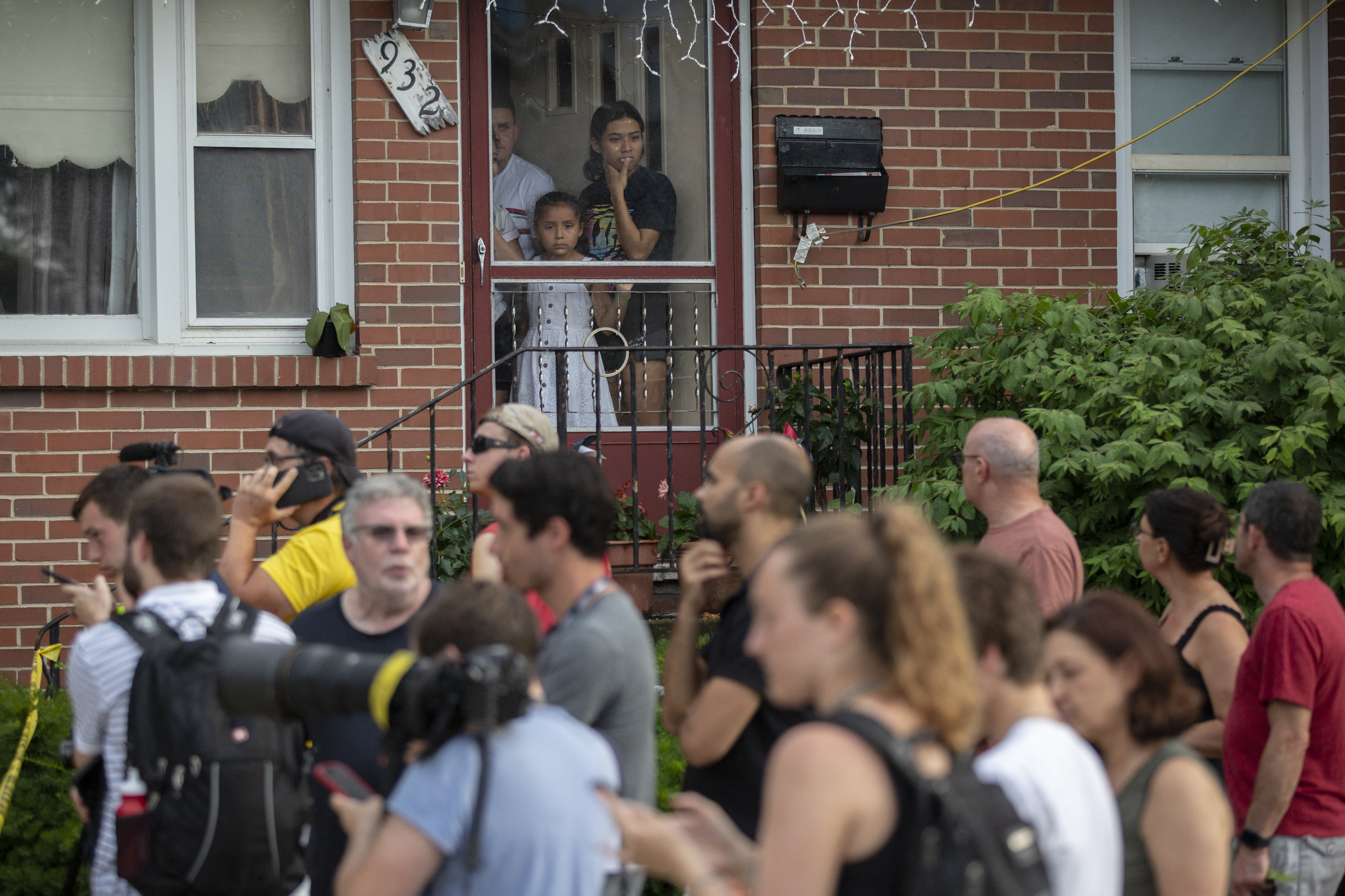 HIGHLAND PARK, IL - JULY 04: A family looks outside of their front door near the home of the mother of the man detained in the mass shooting
