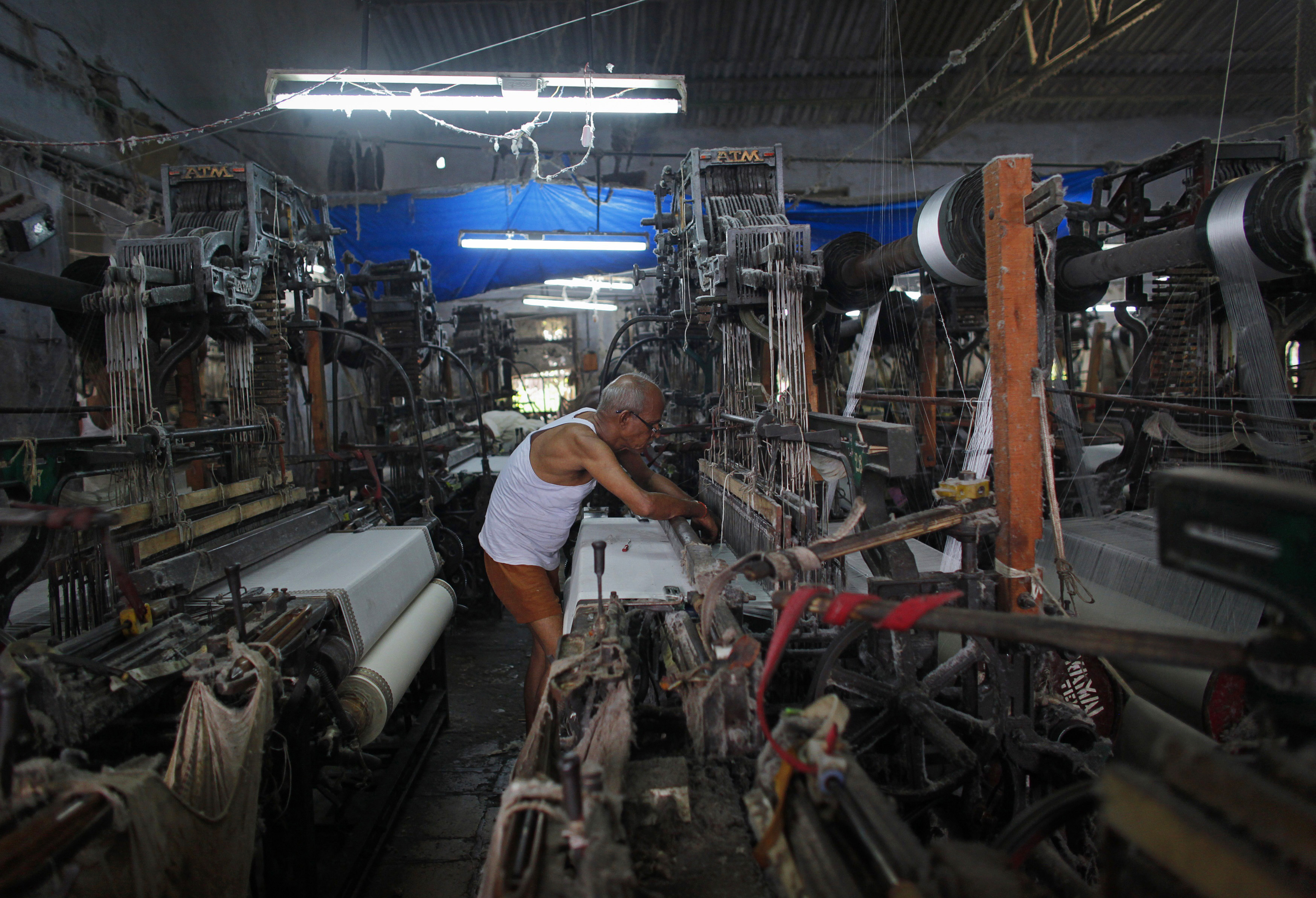 An employee operates a power loom as he weaves saris in Bhiwandi, Maharashtra