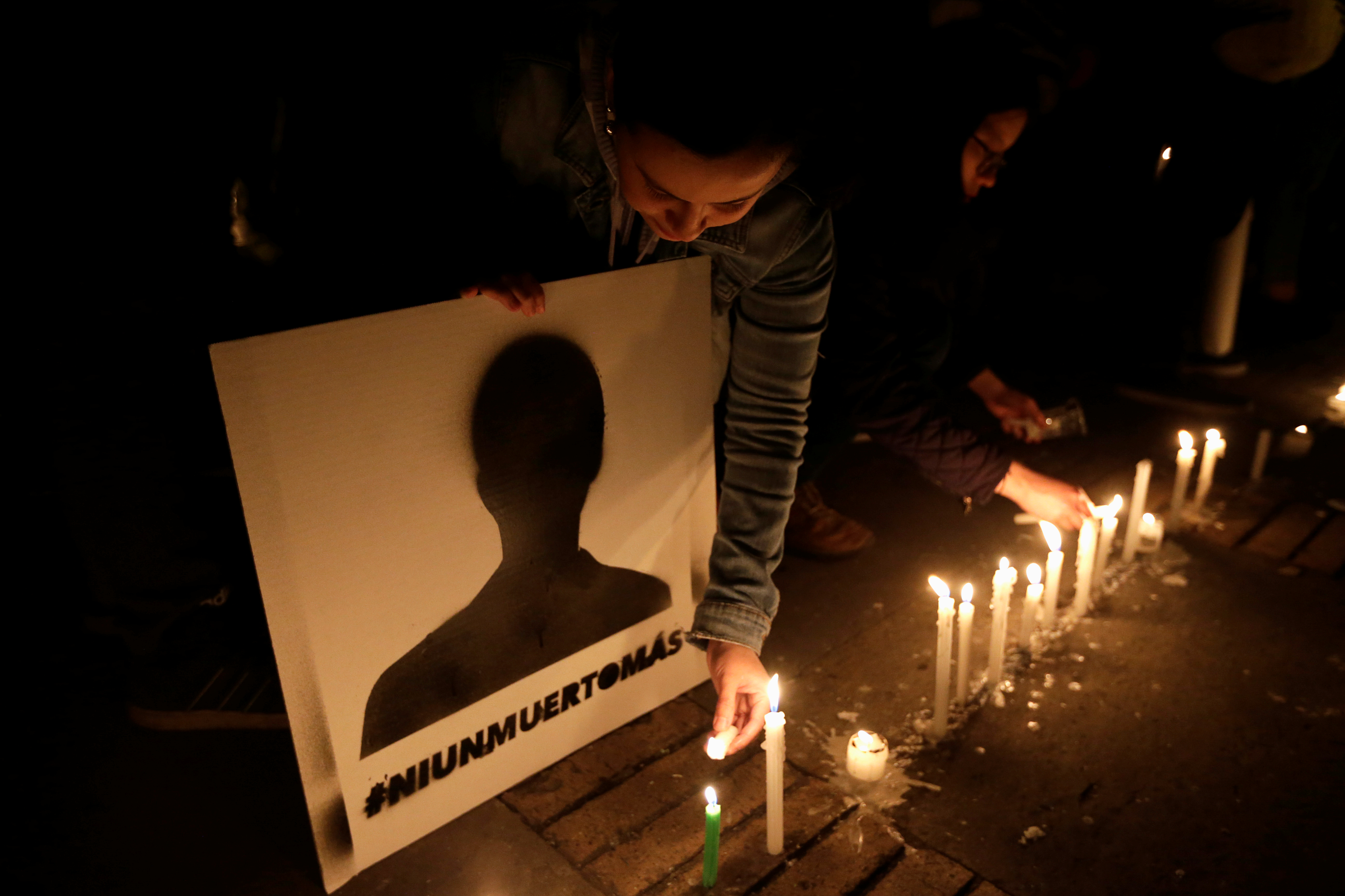 A woman lights a candle during a protest against the killings of social activists in Colombia in 2018