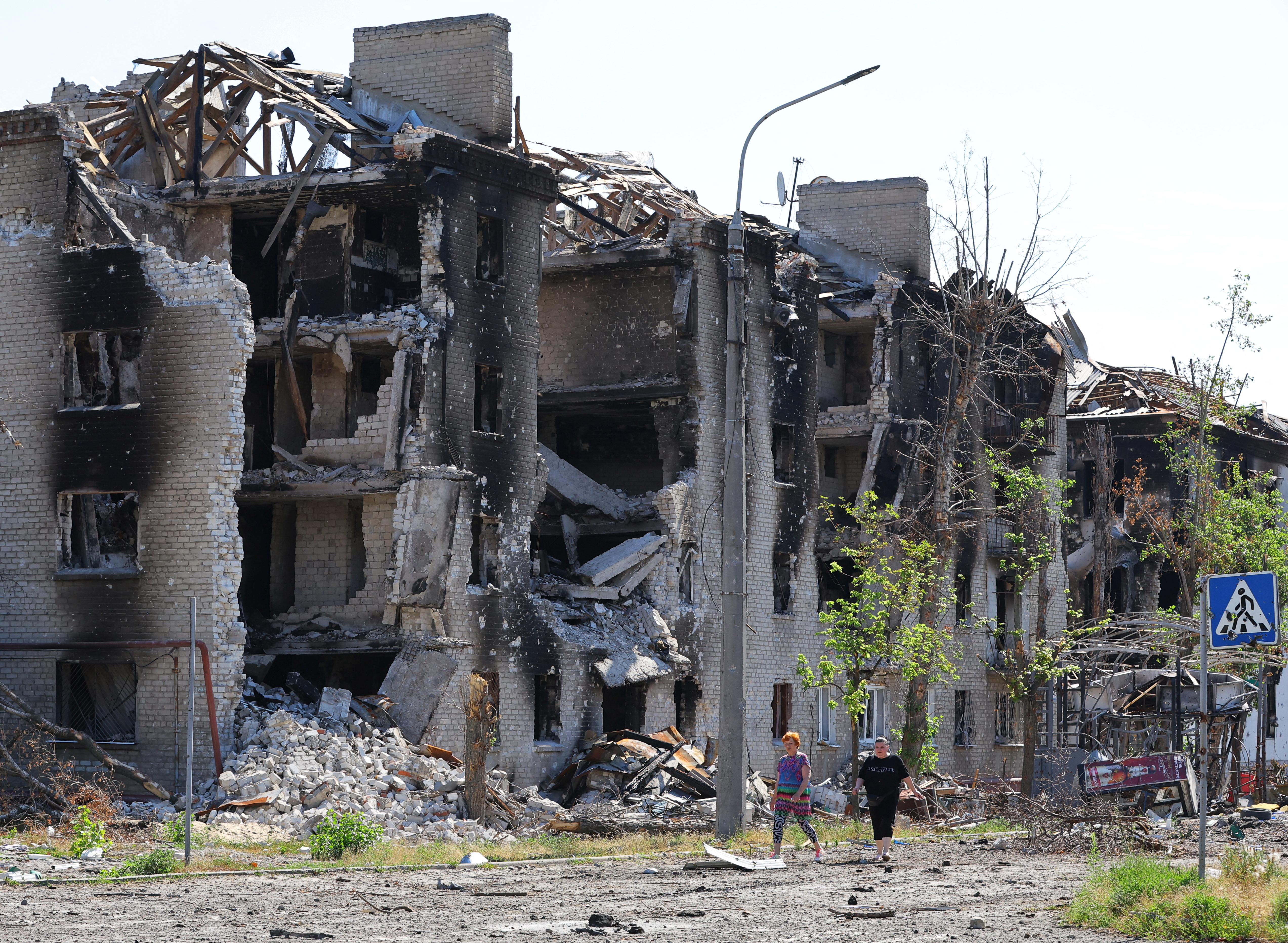Local residents walk past apartment buildings destroyed during Ukraine-Russia conflict in the city of Sievierodonetsk in the Luhansk Region, Ukraine June 30, 2022
