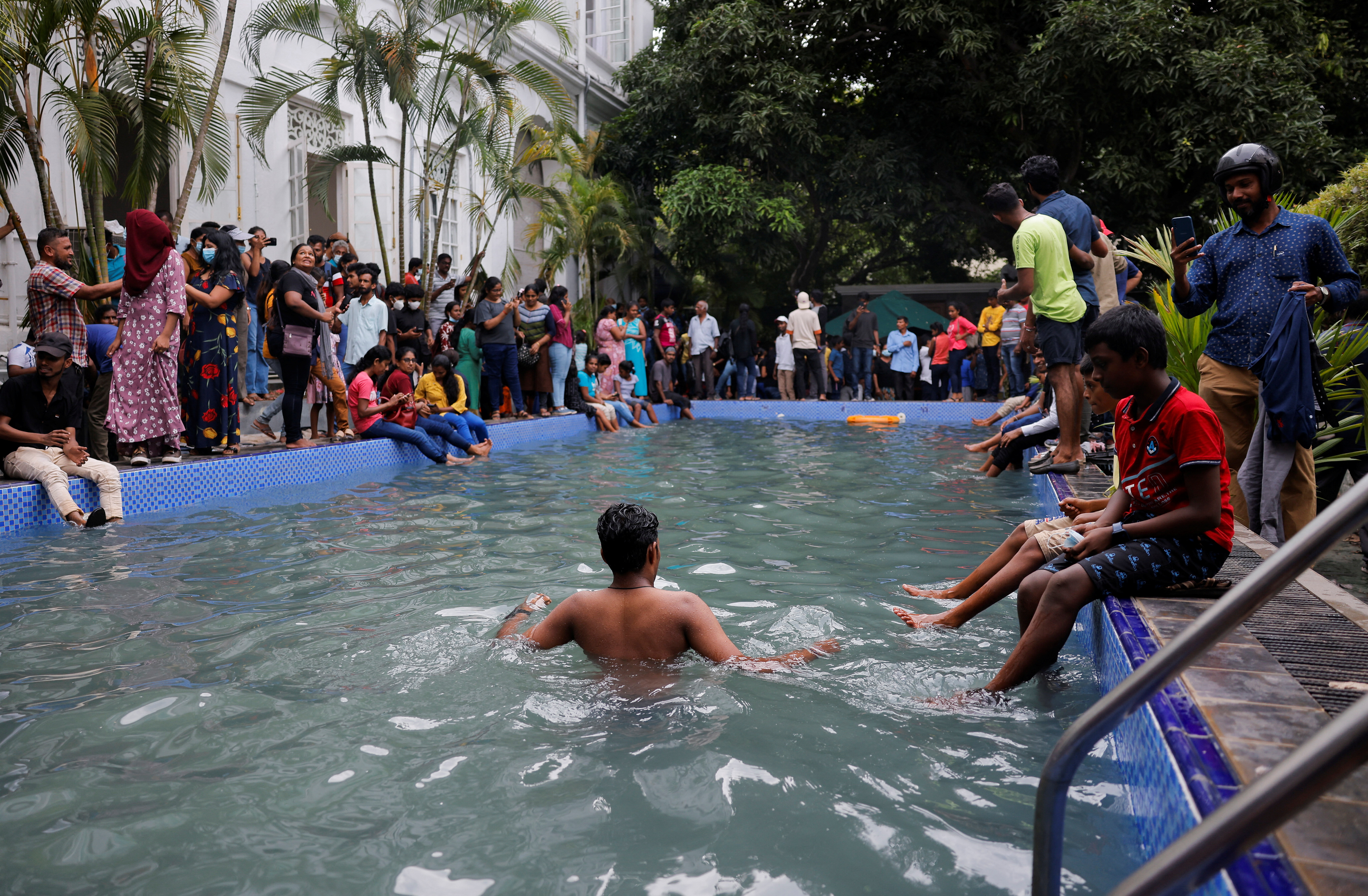 A man stands in the swimming pool as people occupy the president's residence [