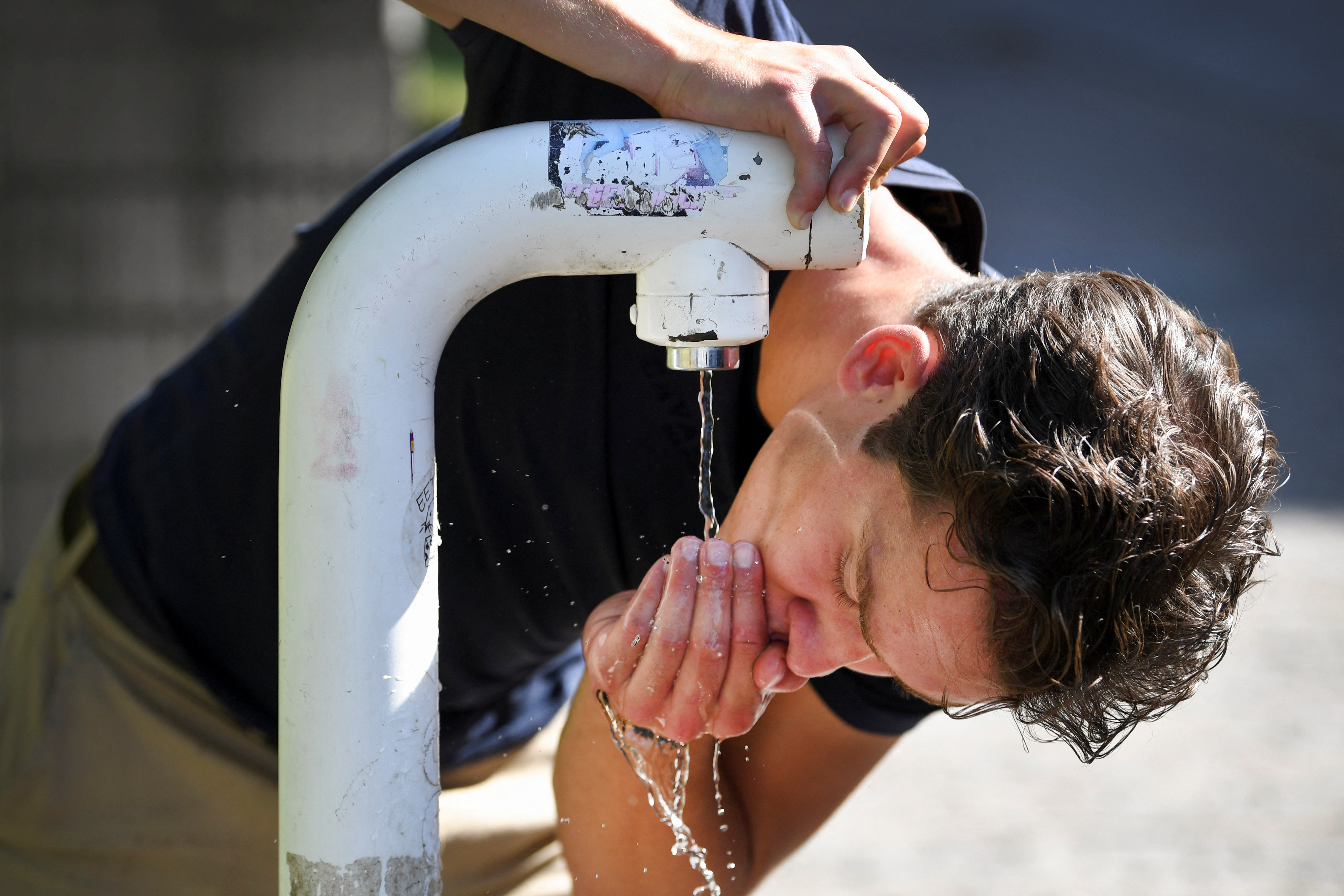 A man drinks water from a public drinking establishment during a heatwave in Nijmegen