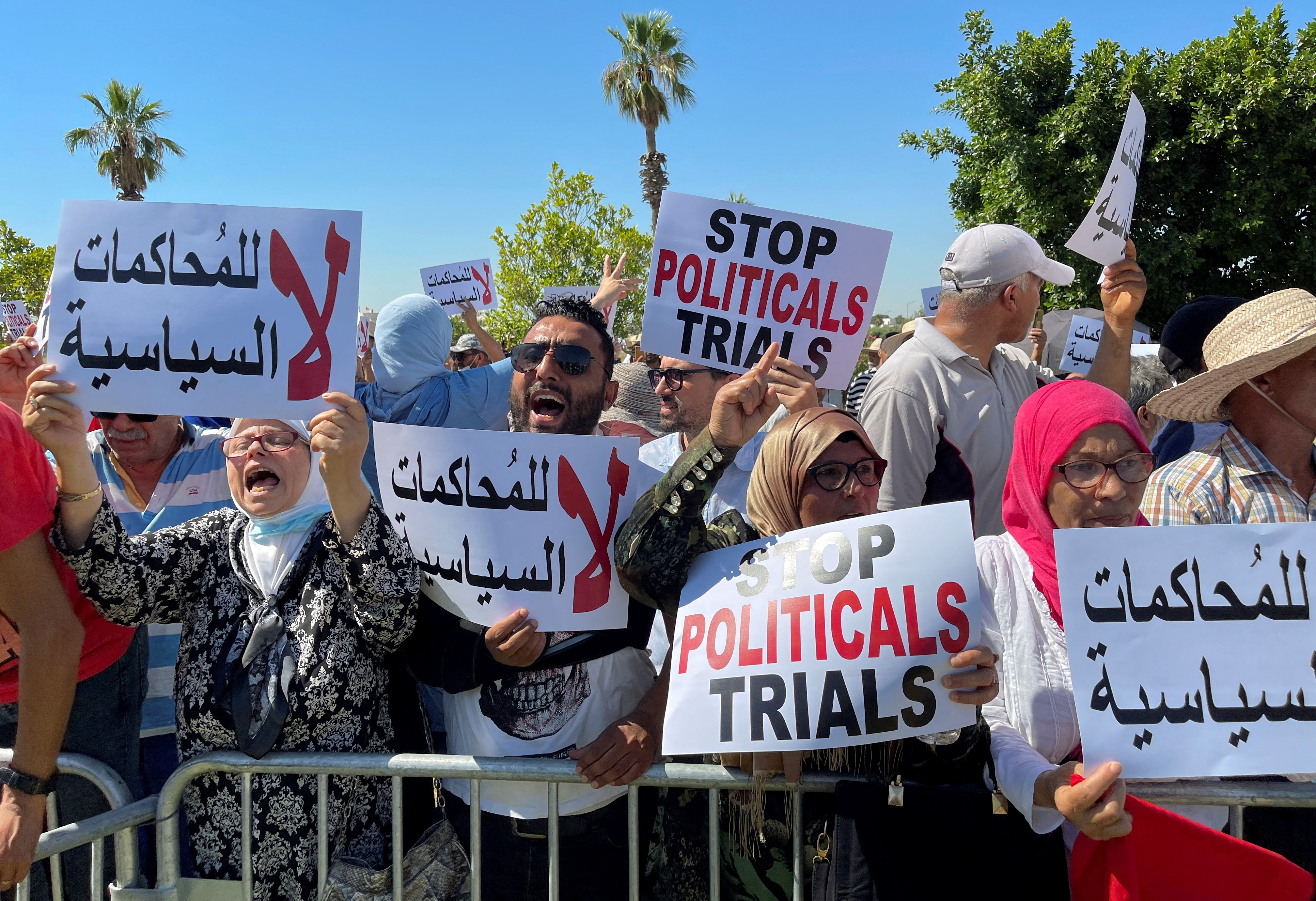 Protesters holding banners saying 'stop political trials' behind a barricade in Tunis