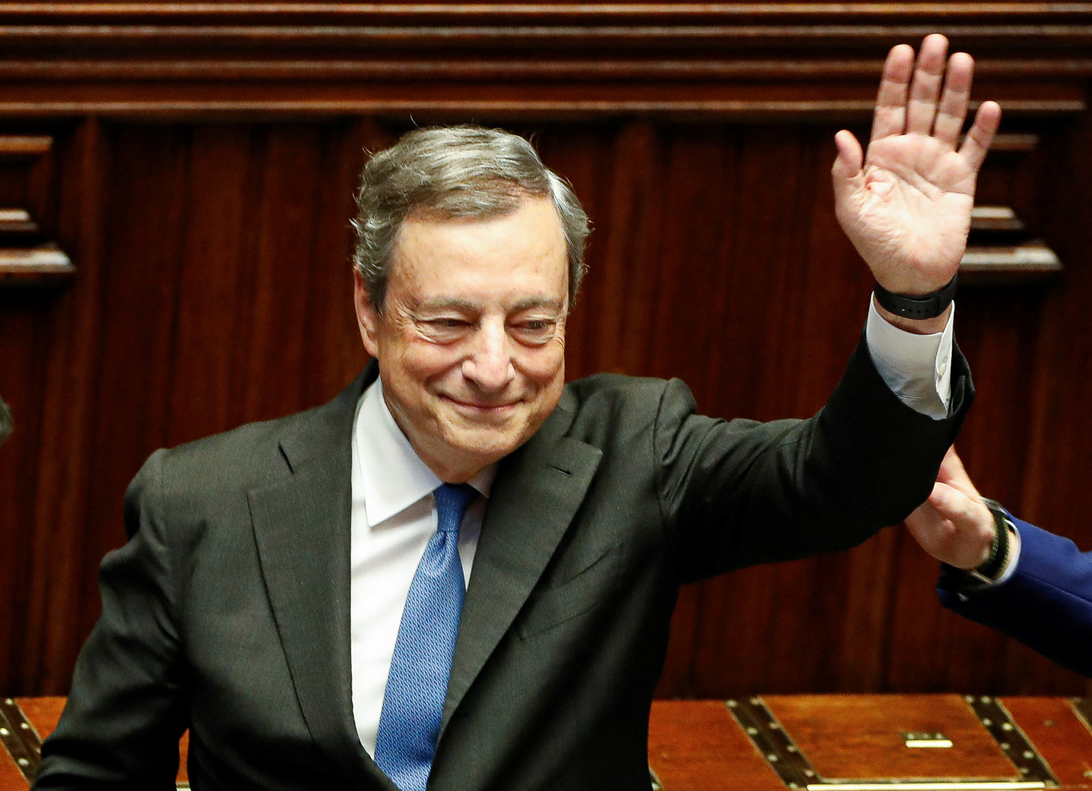 Italy's Prime Minister Mario Draghi waves as he leaves after addressing the lower house of parliament ahead of a vote of confidence for the government.