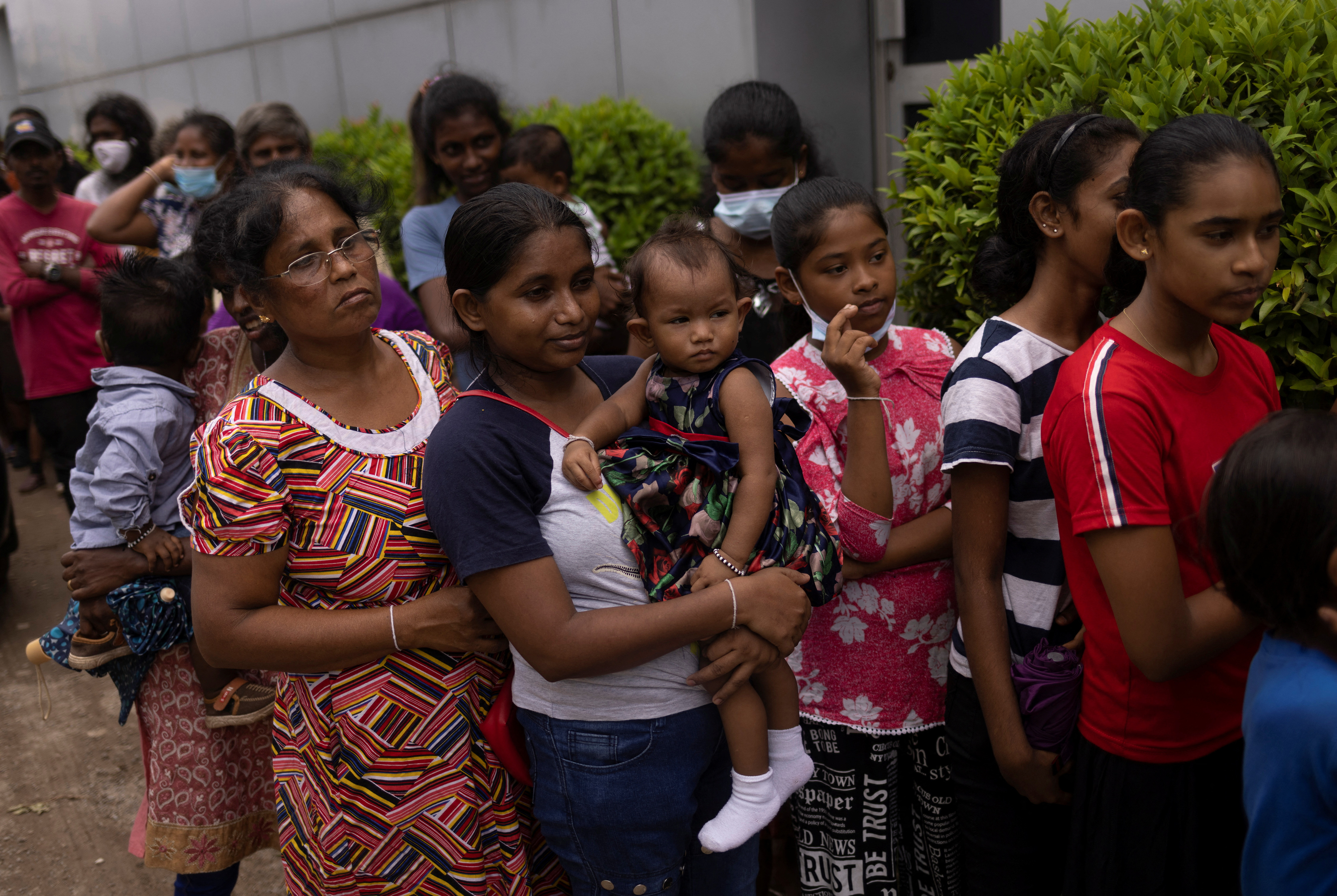 People stand in a queue to receive food at a community kitchen outside a church