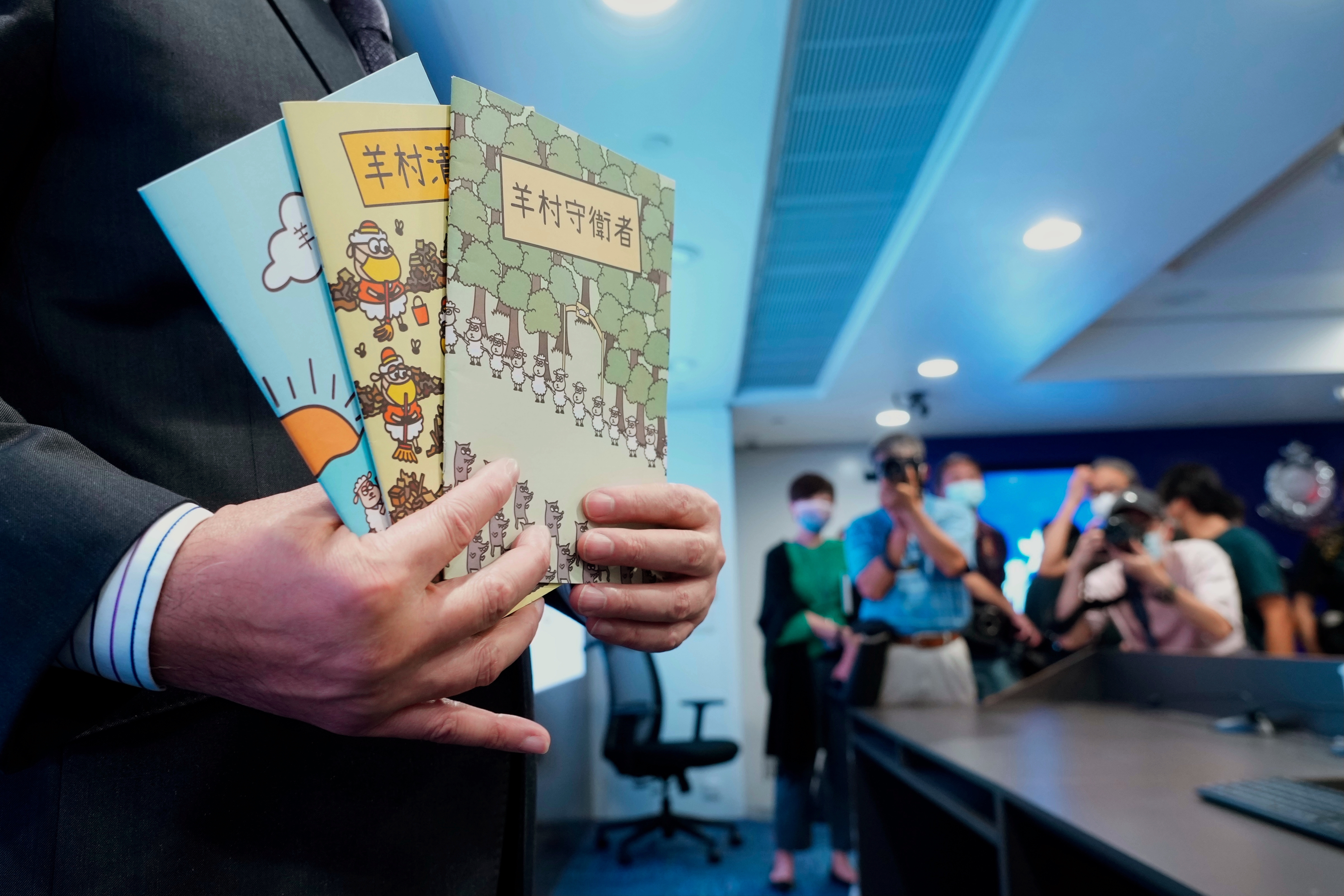 Li Kwai-wah, senior superintendent of Police National Security Department, poses with evidence including three children's books on stories that revolve around a village of sheep which has to deal with wolves from a different village, before a press conference in Hong Kong Thursday, July 22, 2021. Hong Kong's national security police on Thursday arrested five people from a trade union of the General Association of Hong Kong Speech Therapists on suspicion of conspiring to publish and distribute seditious material, in the latest arrests made amid a crackdown on dissent in the city. (AP Photo/Vincent Yu)