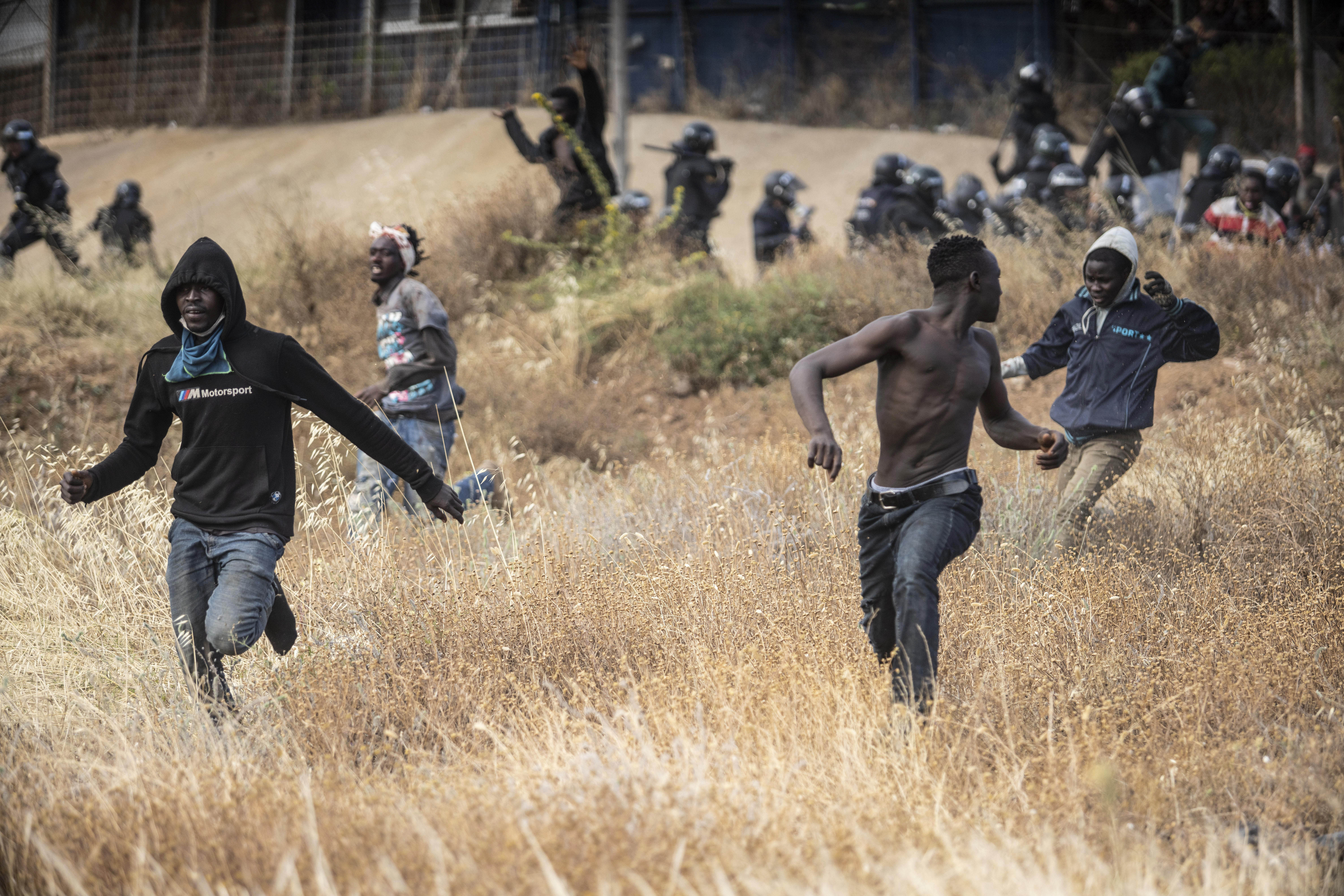 Migrants run on Spanish soil after crossing the fences separating the Spanish enclave of Melilla from Morocco in Melilla, Spain