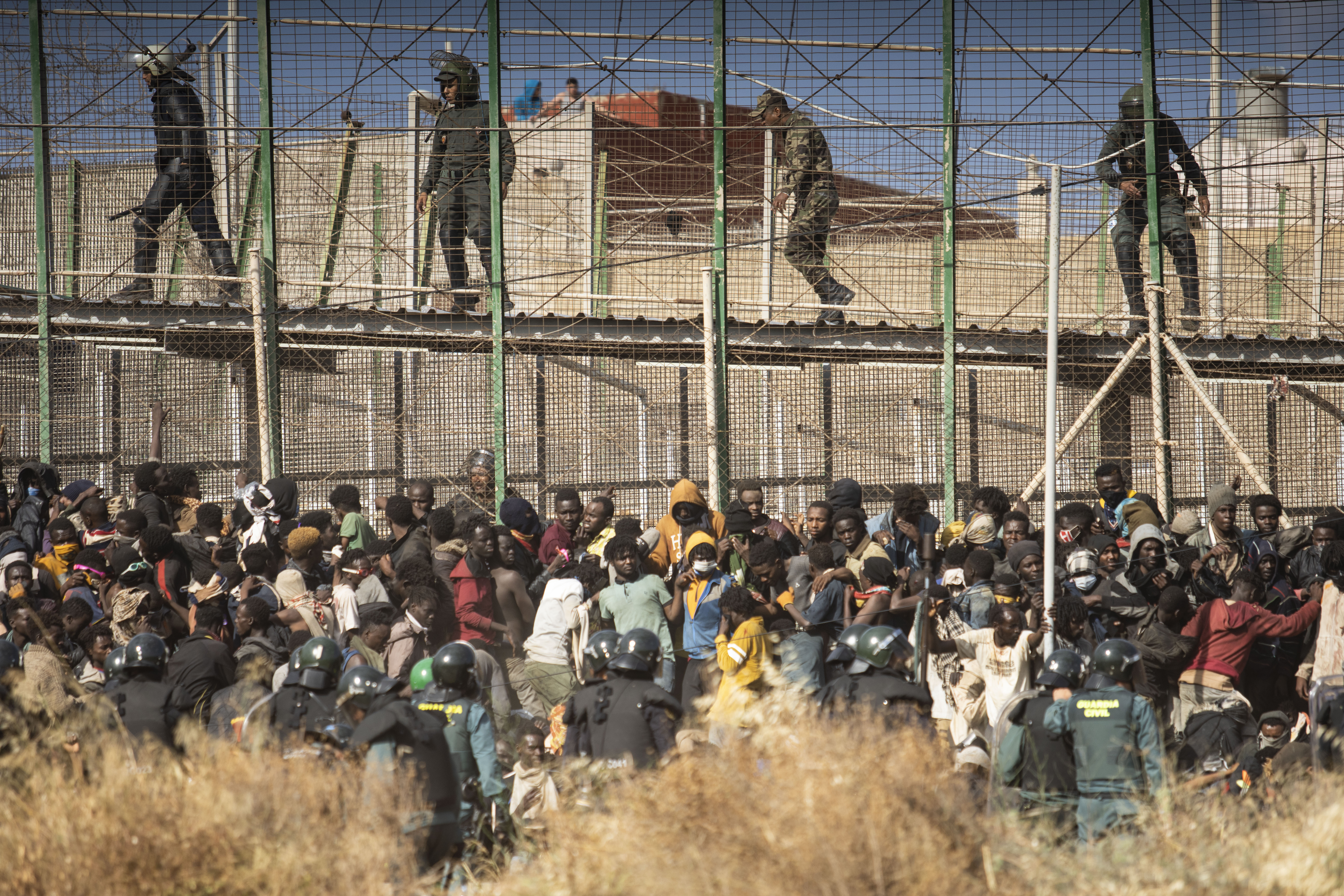 Riot police officers cordon off the area after migrants arrive on Spanish soil and crossing the fences separating the Spanish enclave of Melilla from Morocco in Melilla, Spain
