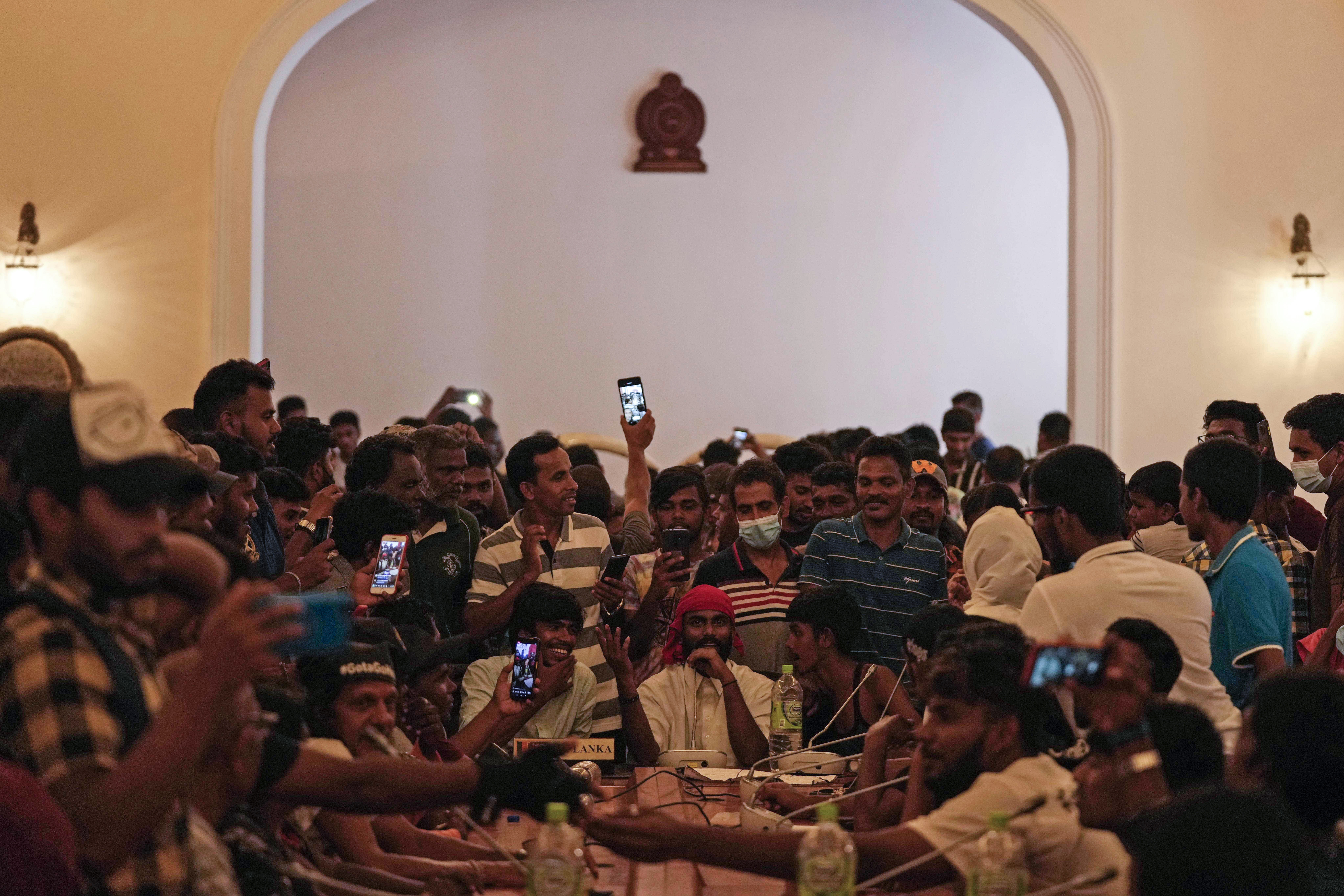Protesters pretend to hold a cabinet meeting after occupying seats at the cabinet meeting hall of president's official residence a day after it was stormed in Colombo, Sri Lanka