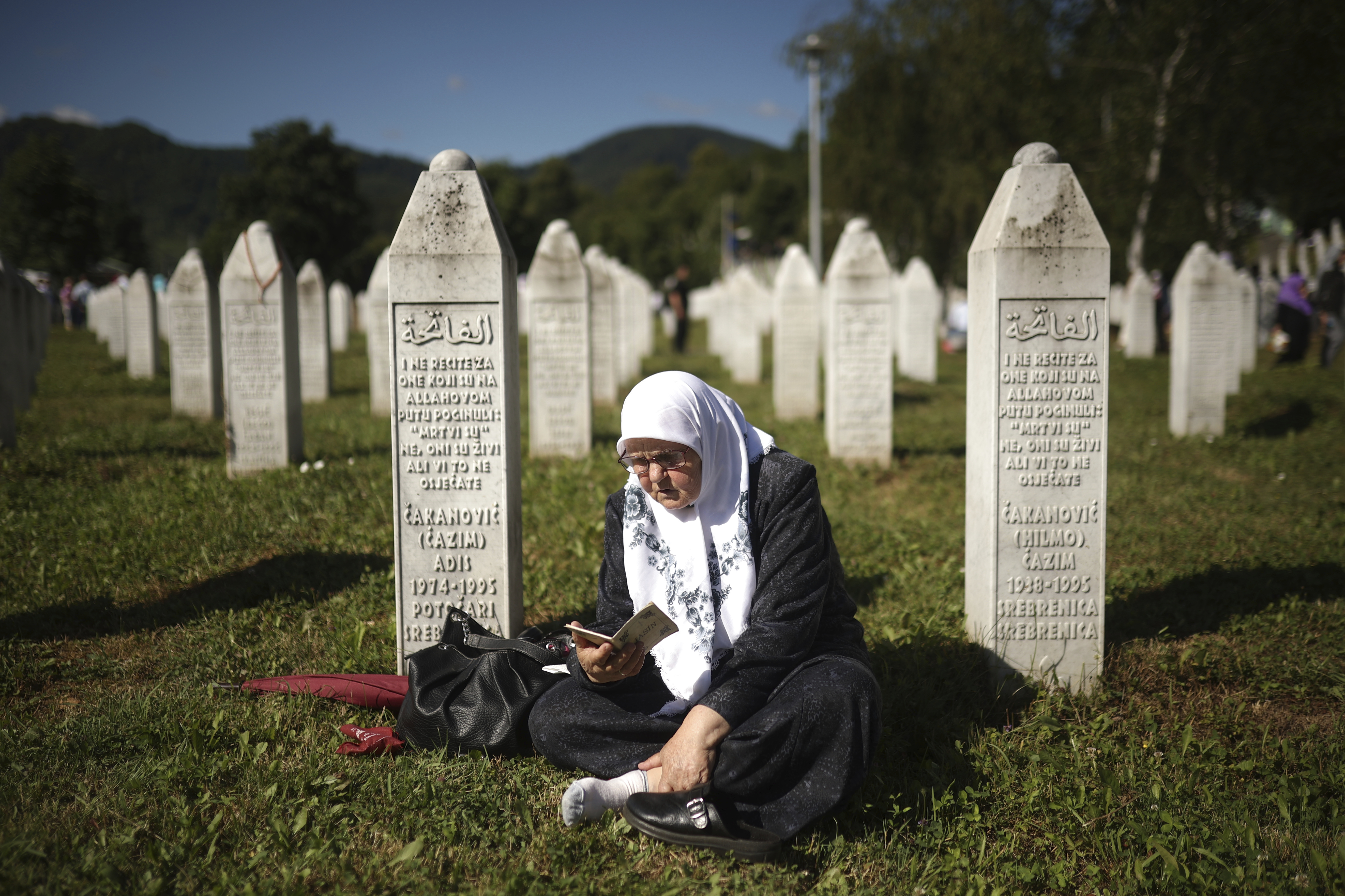A Bosnian muslim woman prays at a grave in Memorial Centre in Potocari