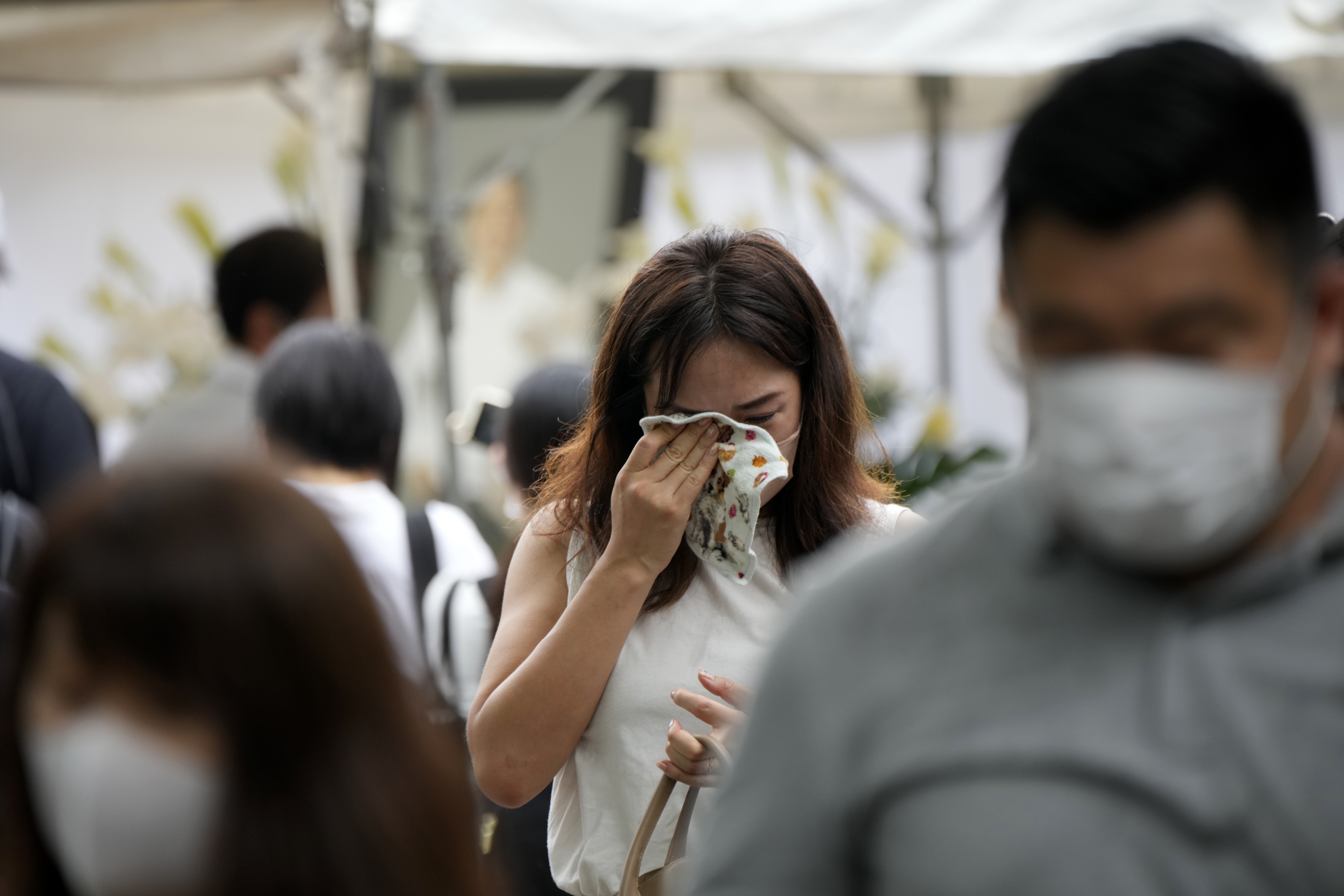 One of people who offer flowers and prayers for former Prime Minister Shinzo Abe, cries at Zojoji temple in Tokyo