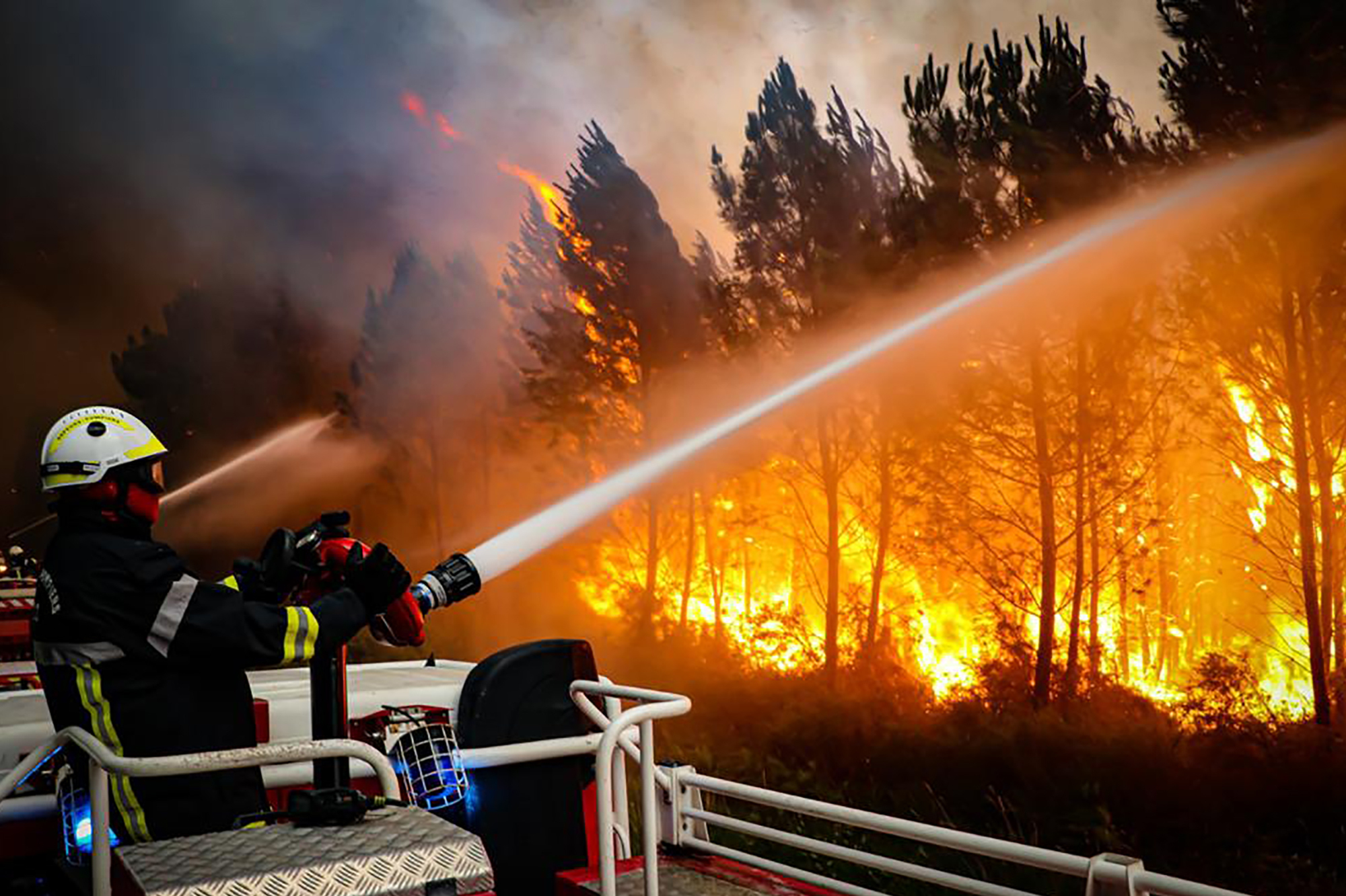 firefighters using hose to fight a wildfire near Landiras, southwestern France,