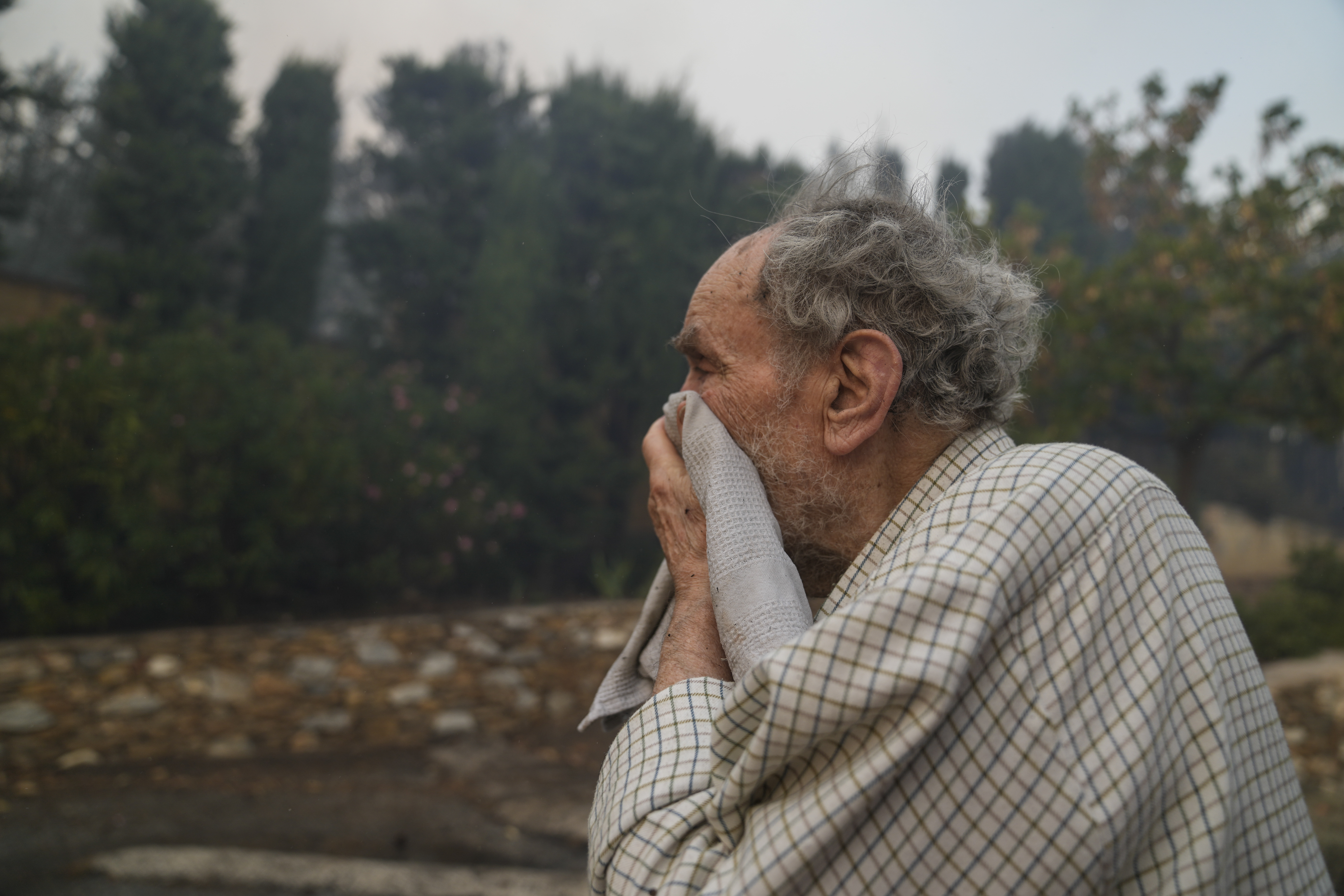 A man looks on as the flames approach his house in Penteli,