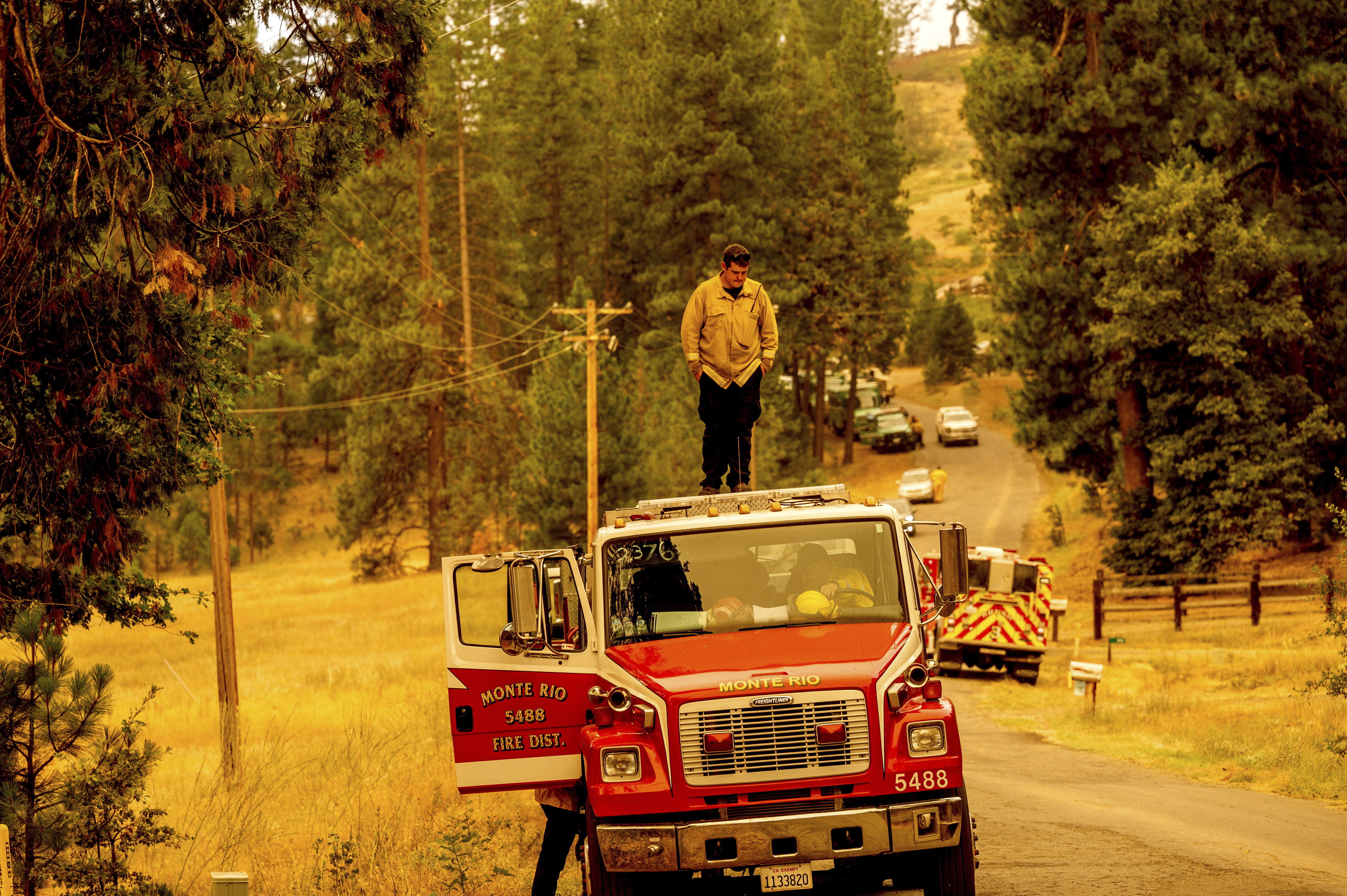 A firefighter stands atop a fire engine shortly after coming on duty to battle the Oak Fire