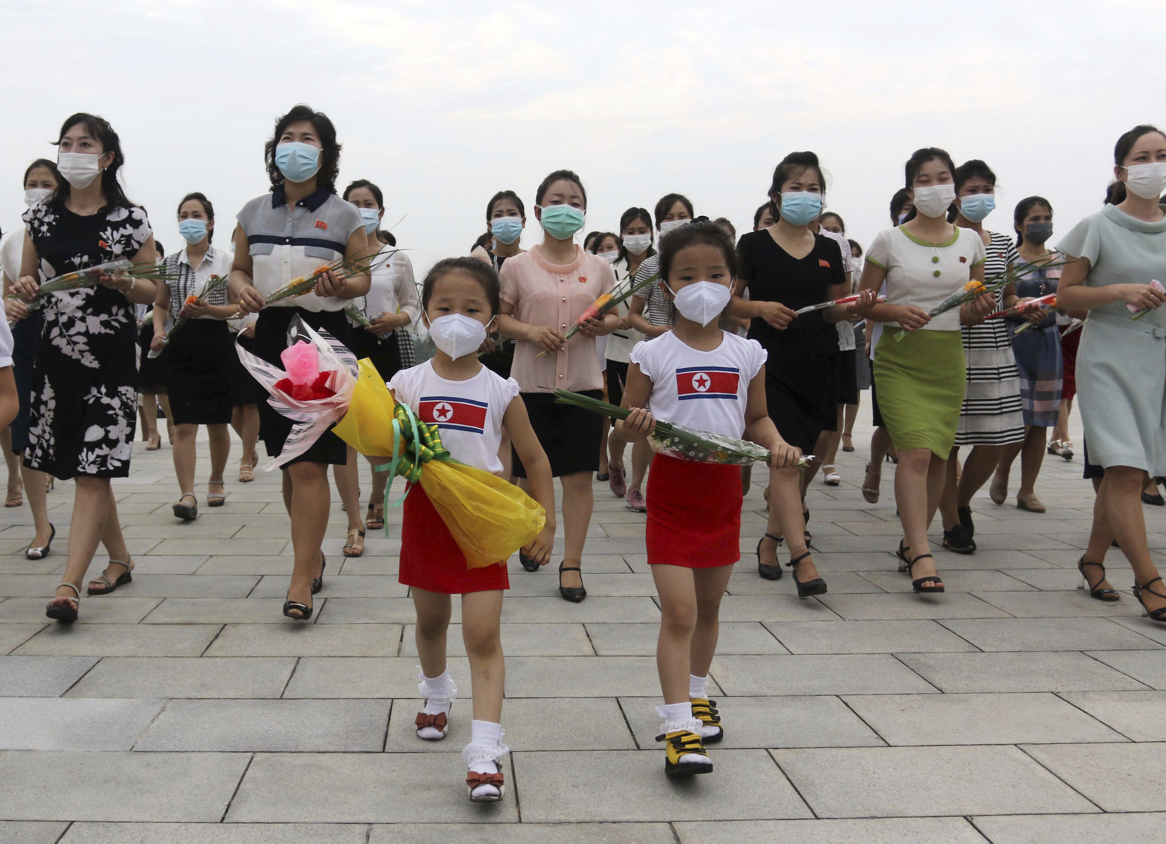 Two young girls in front and women behind them walk with flowers in hand as they visit the statues of former North Korean leaders Kim Il Sung and Kim Jong Il on Mansu Hill in Pyongyang, North Korea, Wednesday, July 27, 2022, on the occasion of the 69th anniversary of the end of the Korean War.