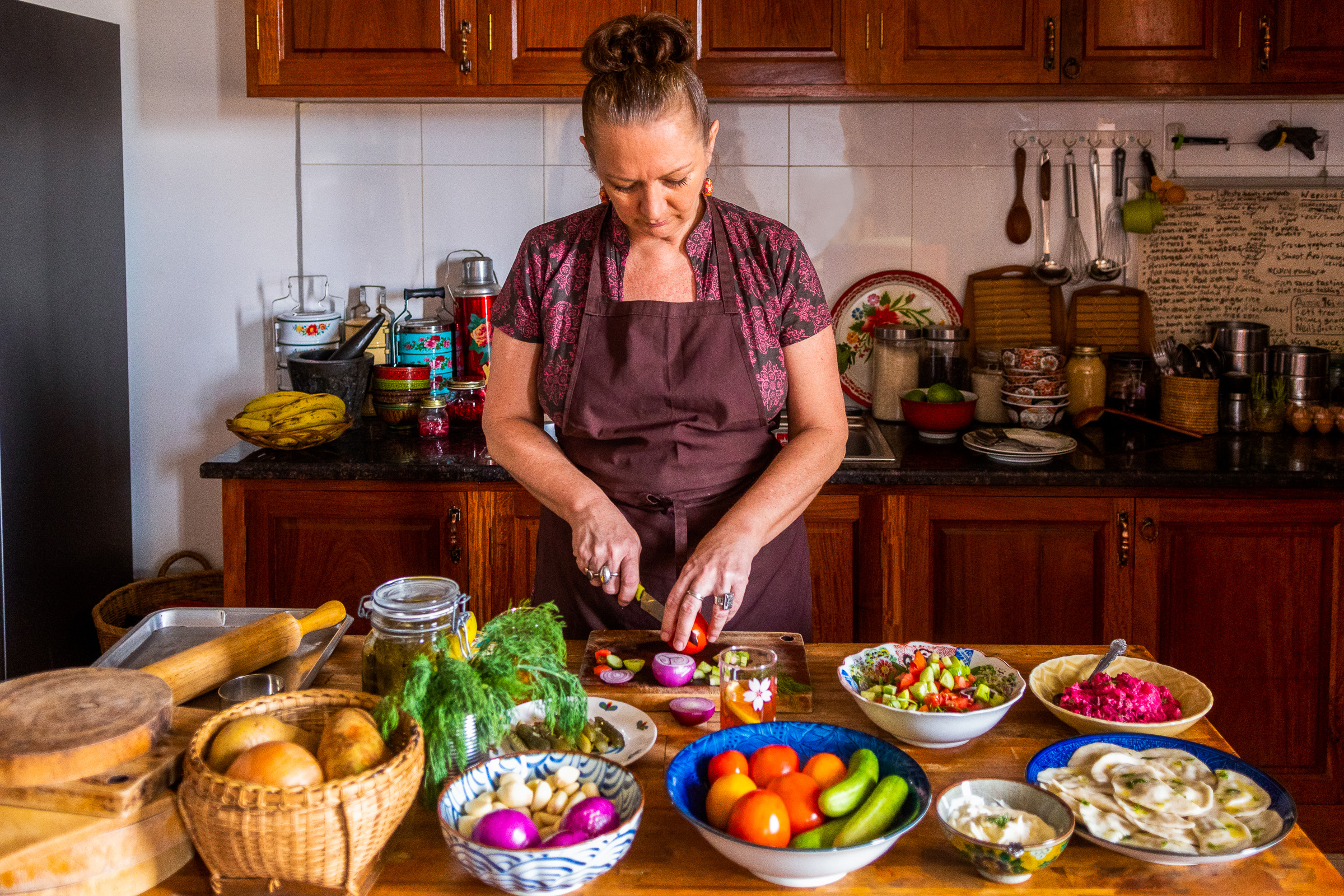 A shot of the author standing preparing food at her kitchen table