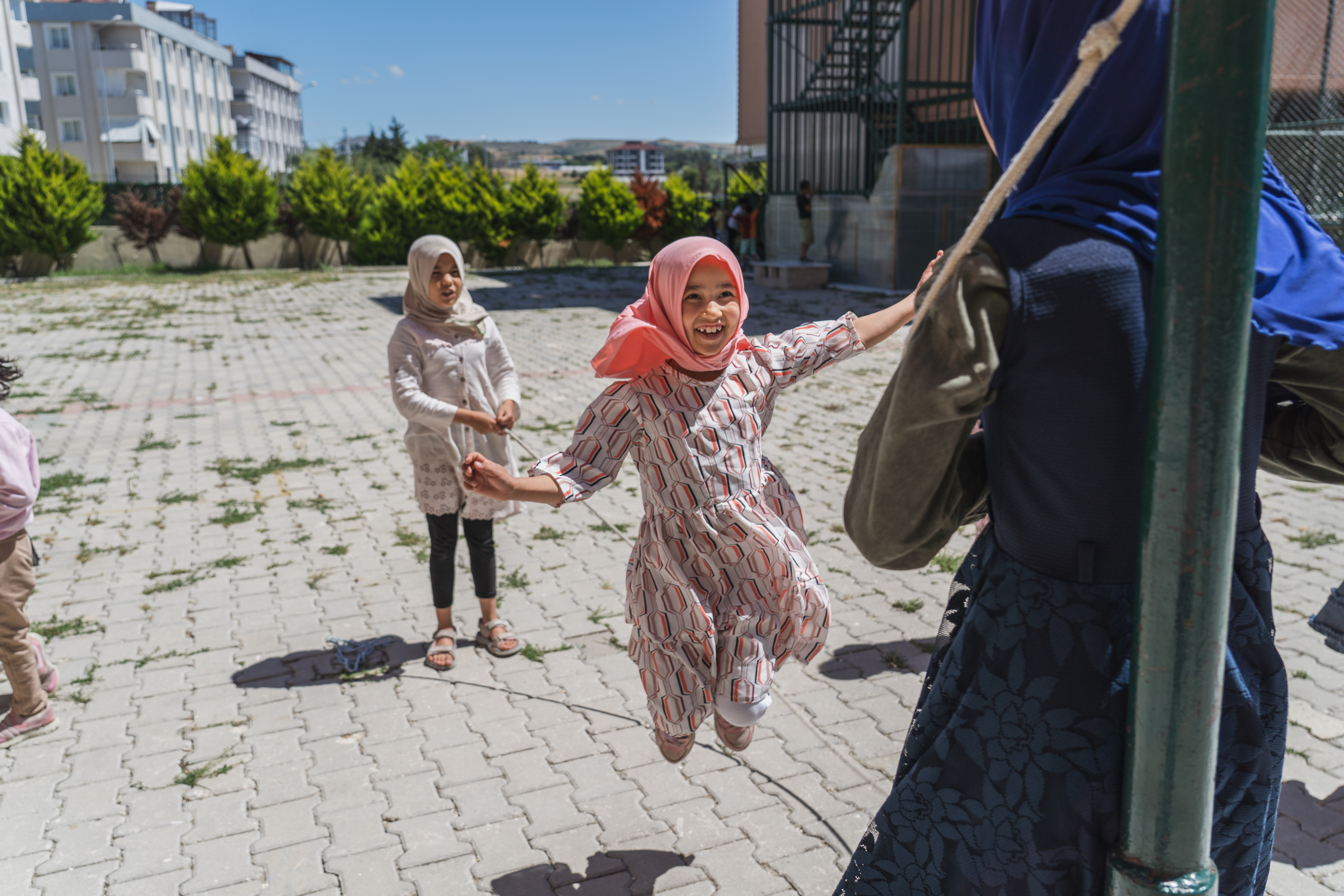 A photo of three girls playing jump rope outside.