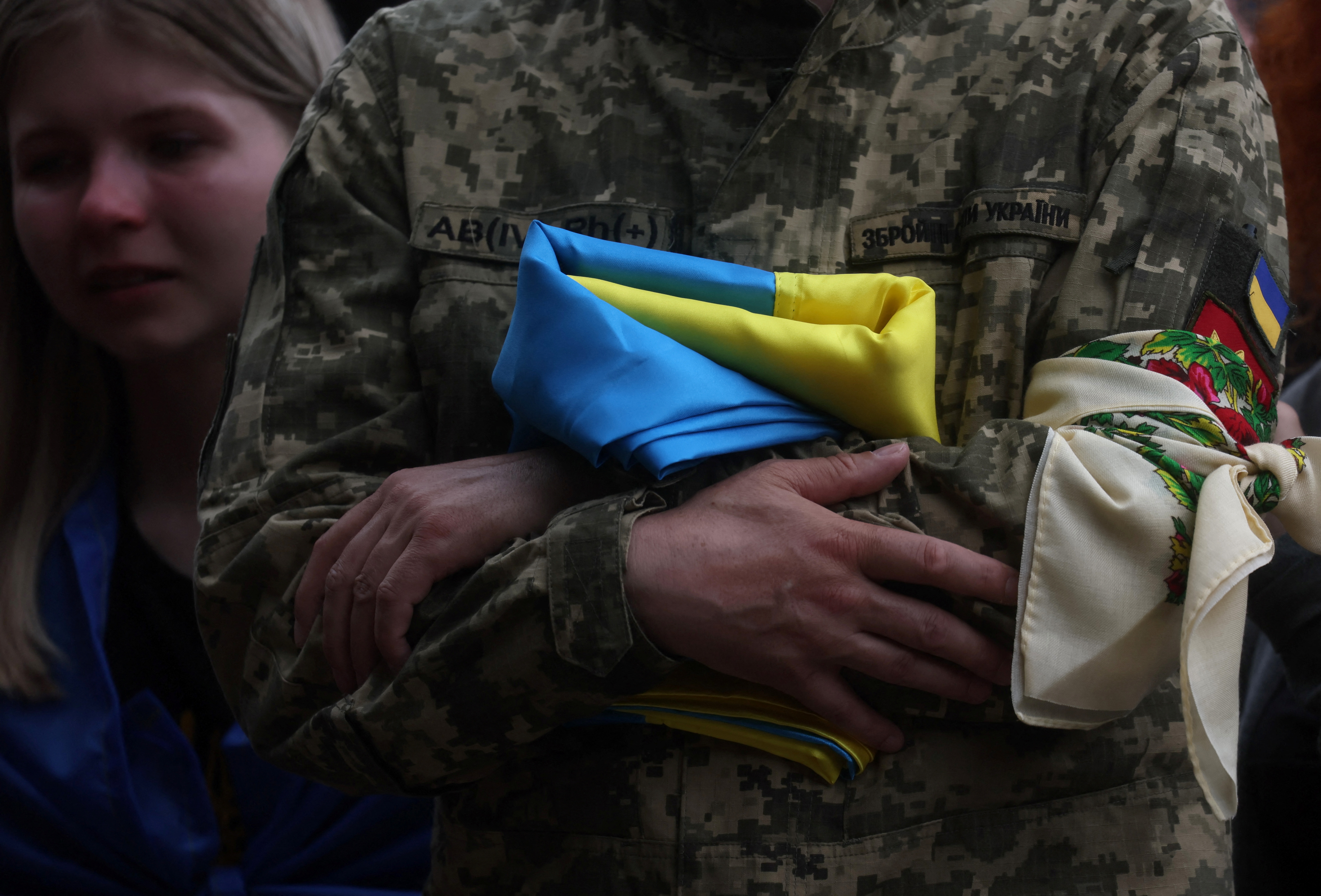 A father holds a Ukrainian flag during his son's funeral in Kyiv, Ukraine.