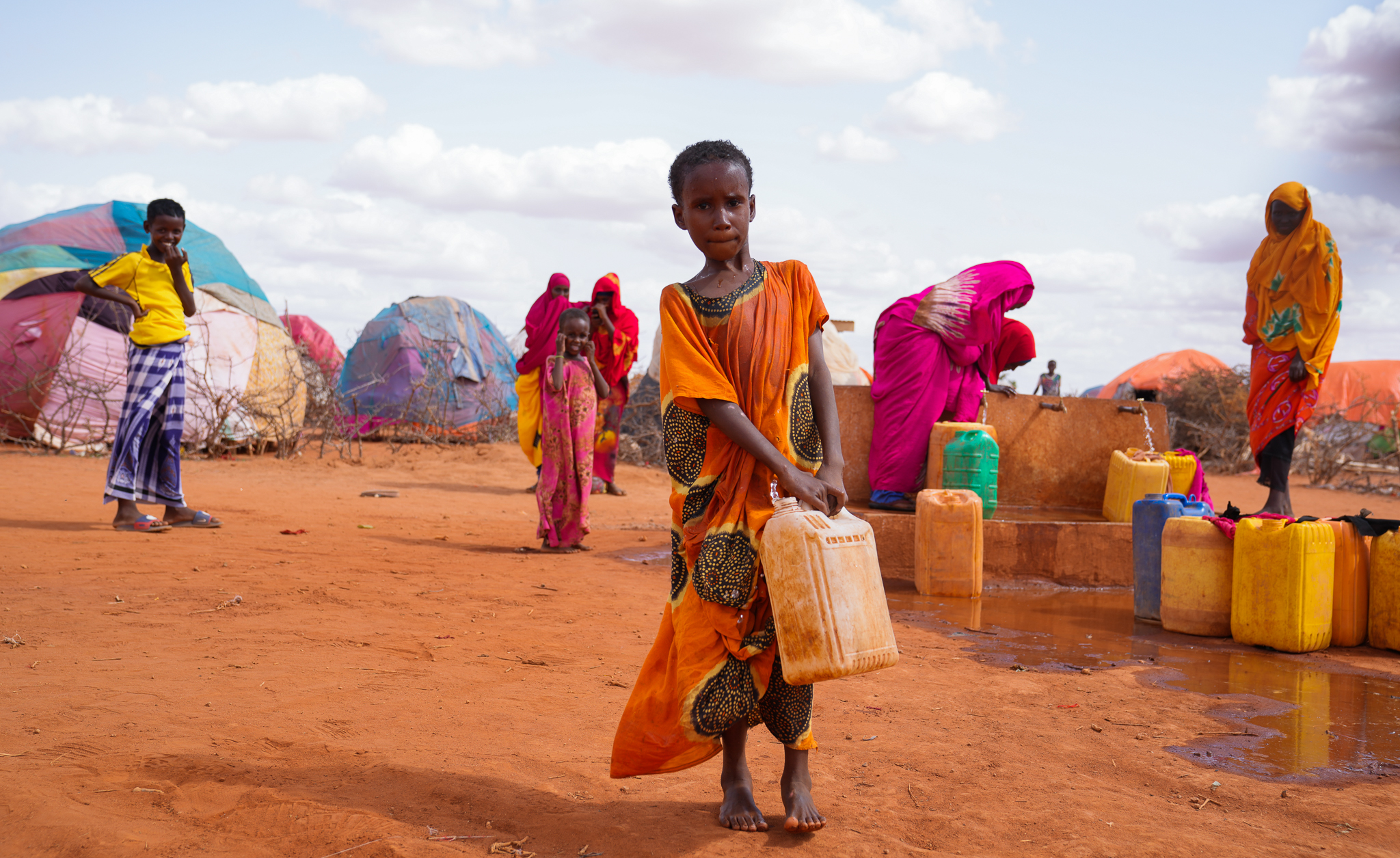 0-year-old Hibo carries water in a jerrycan to her temporary house at Kaharey IDP camp in Dollow, Somalia.