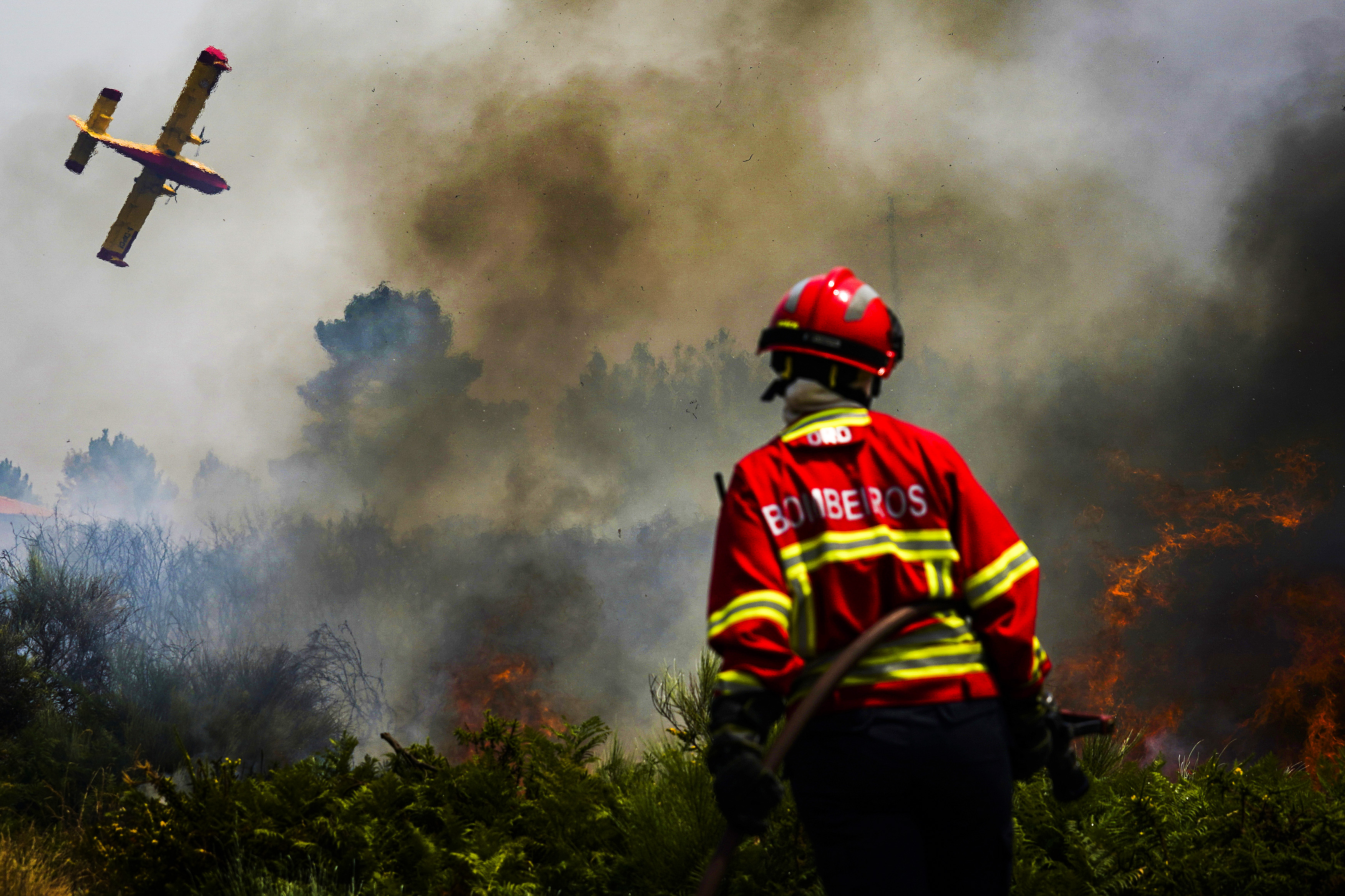 A firefighter fights the flames surrounding Ancede village during a wildfire in the municipality of Baiao, North of Portuga