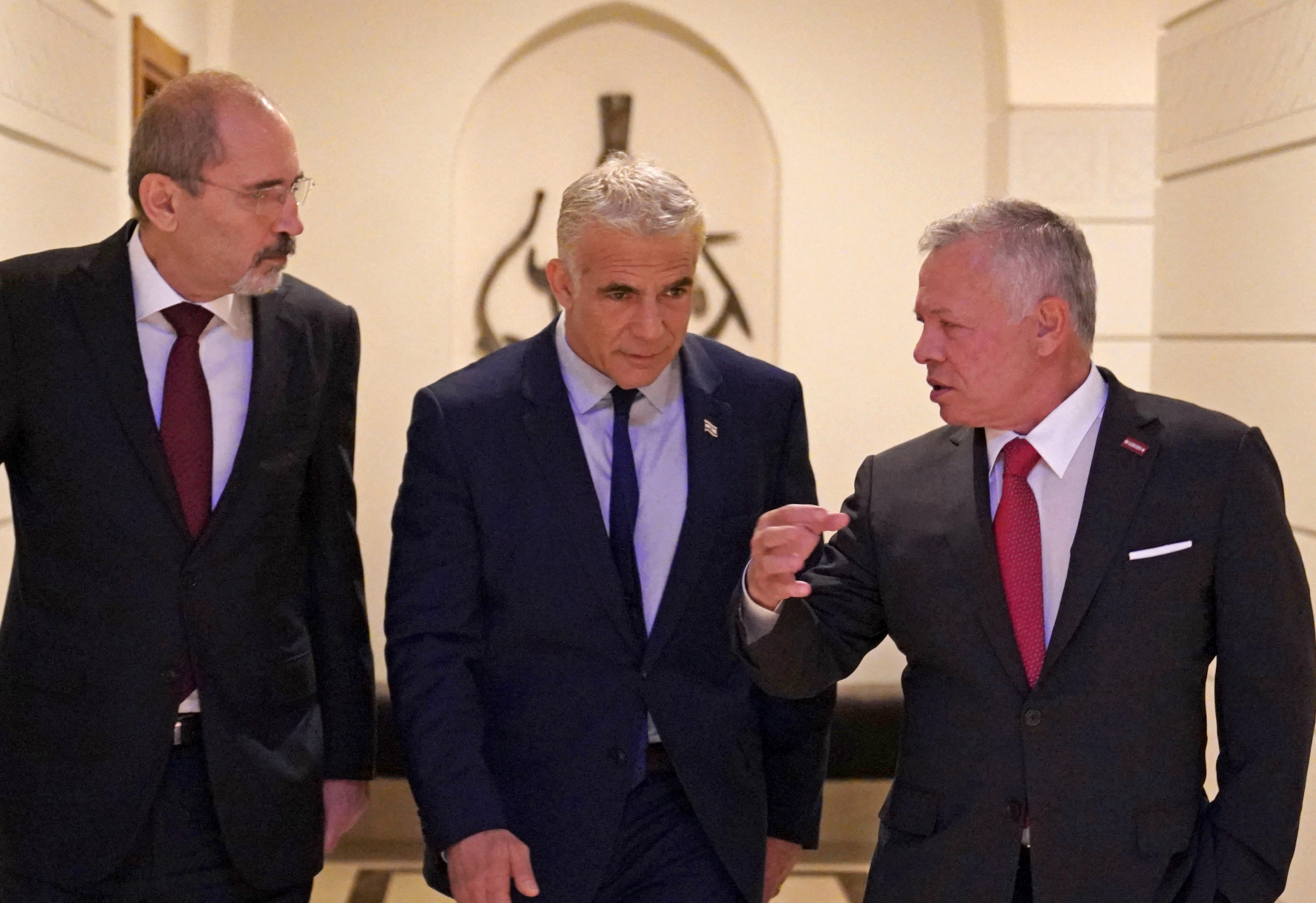 This handout picture released by the Jordanian Royal Palace shows Jordan's King Abdullah II (R) and Jordan's Foreign Minister Ayman Safadi (L) receiving Israeli Prime Minister Yair Lapid at al-Husseiniya Palace in Amman