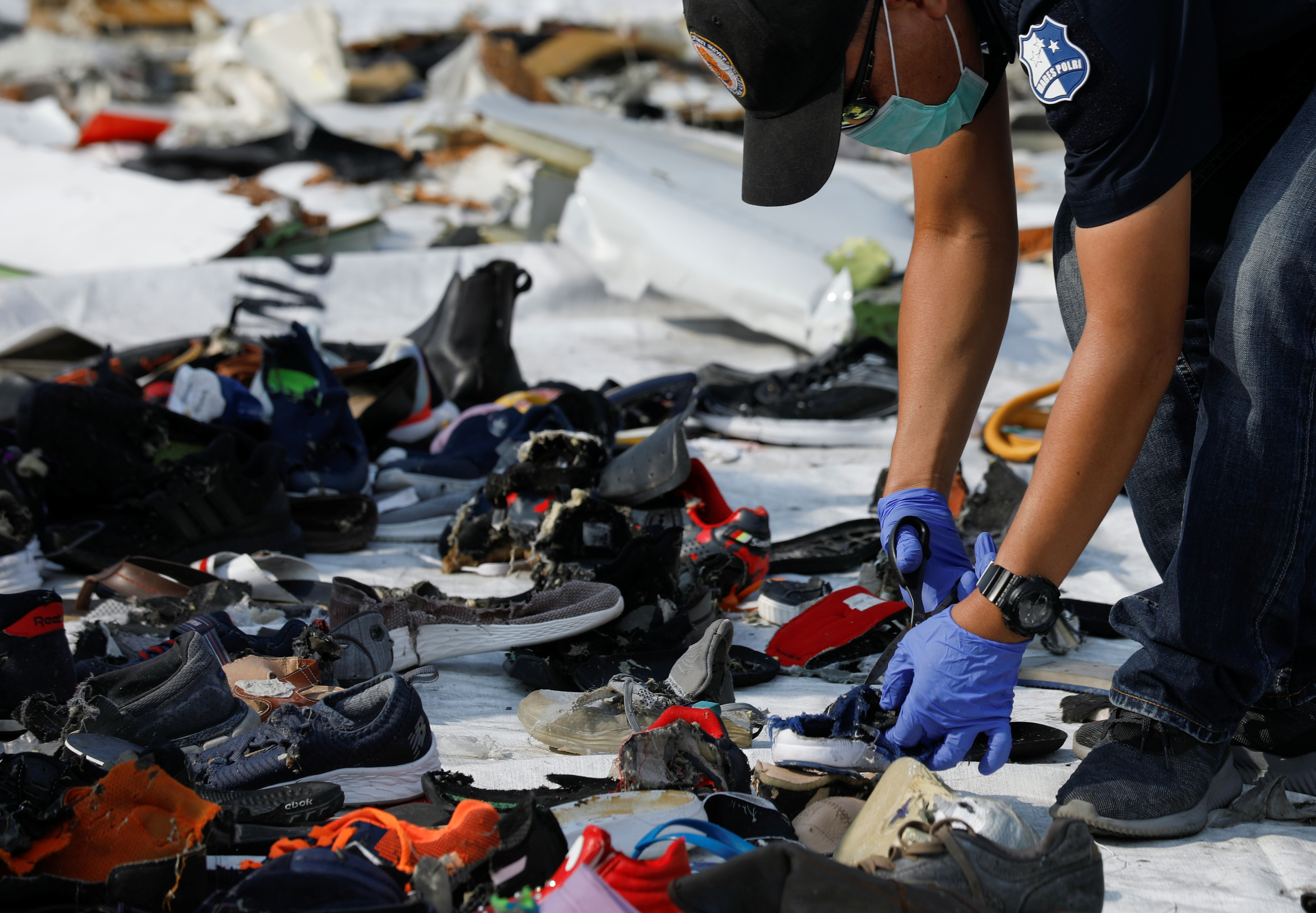 An investigator collects the Lion Air crash victims' belongings at the scene of the accident.