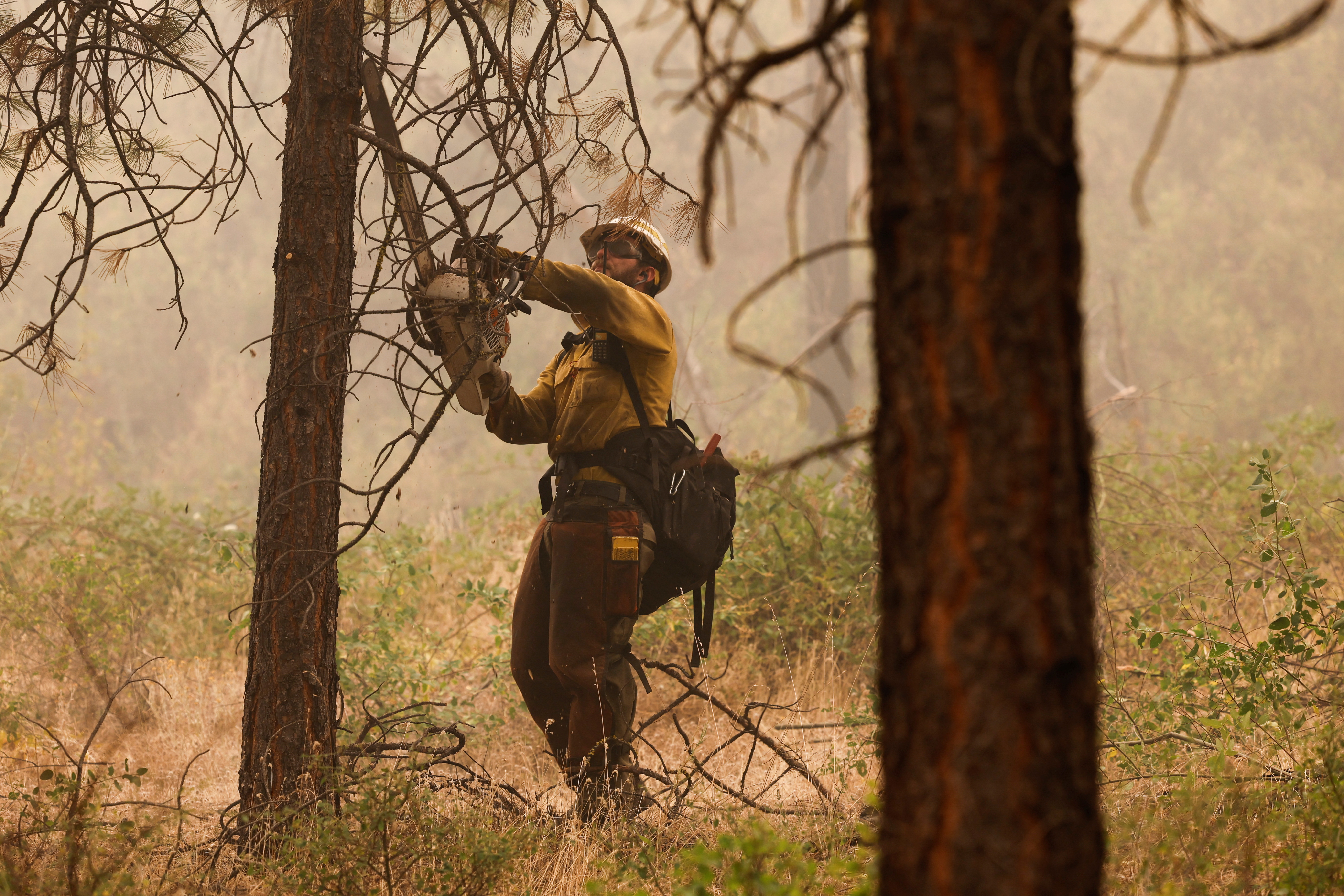 A U.S. Forest Service firefighter clears brush as the McKinney Fire continues burning near Yreka, California
