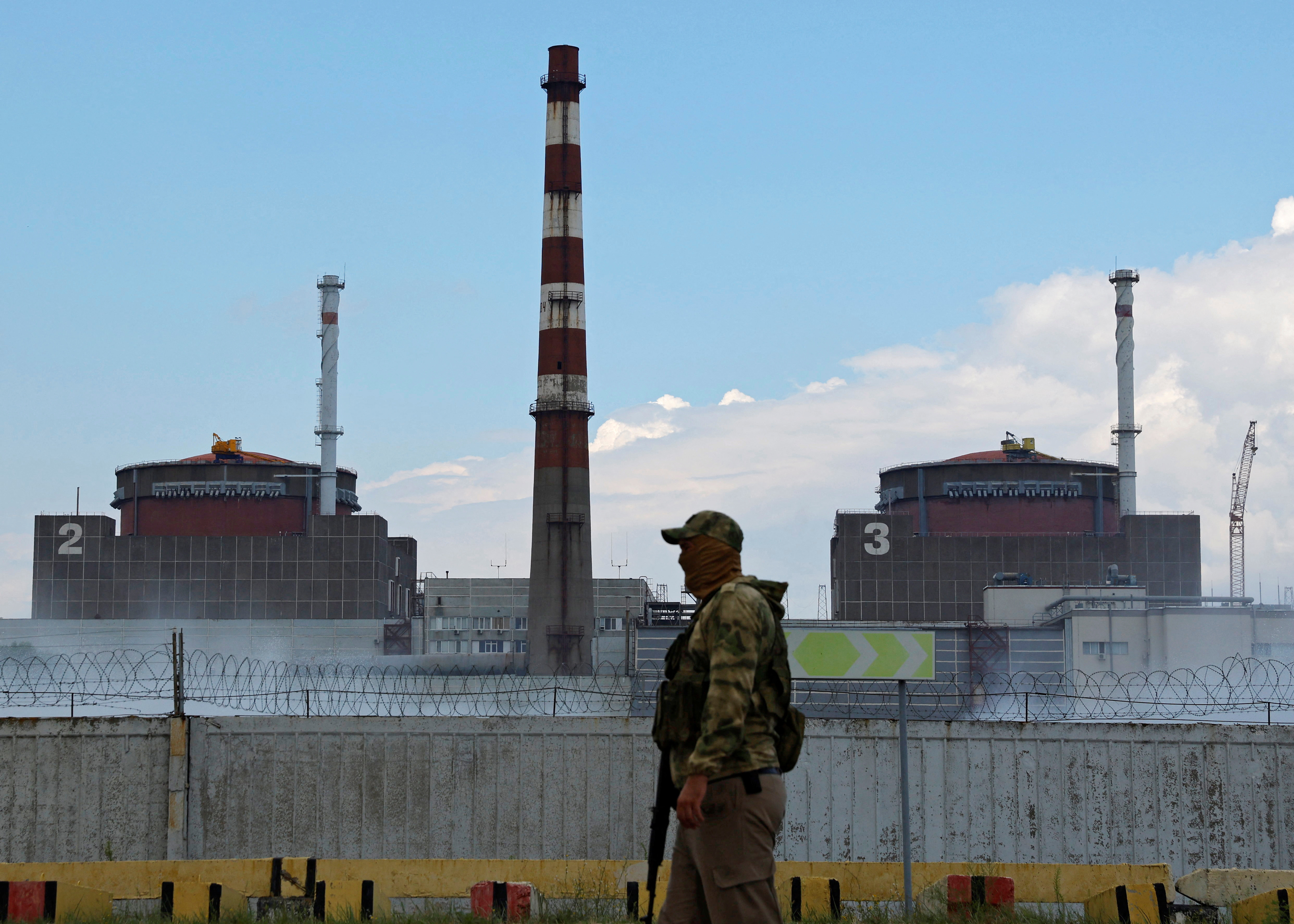 A serviceman with a Russian flag on his uniform stands guard near the Zaporizhzhia Nuclear Power Plant