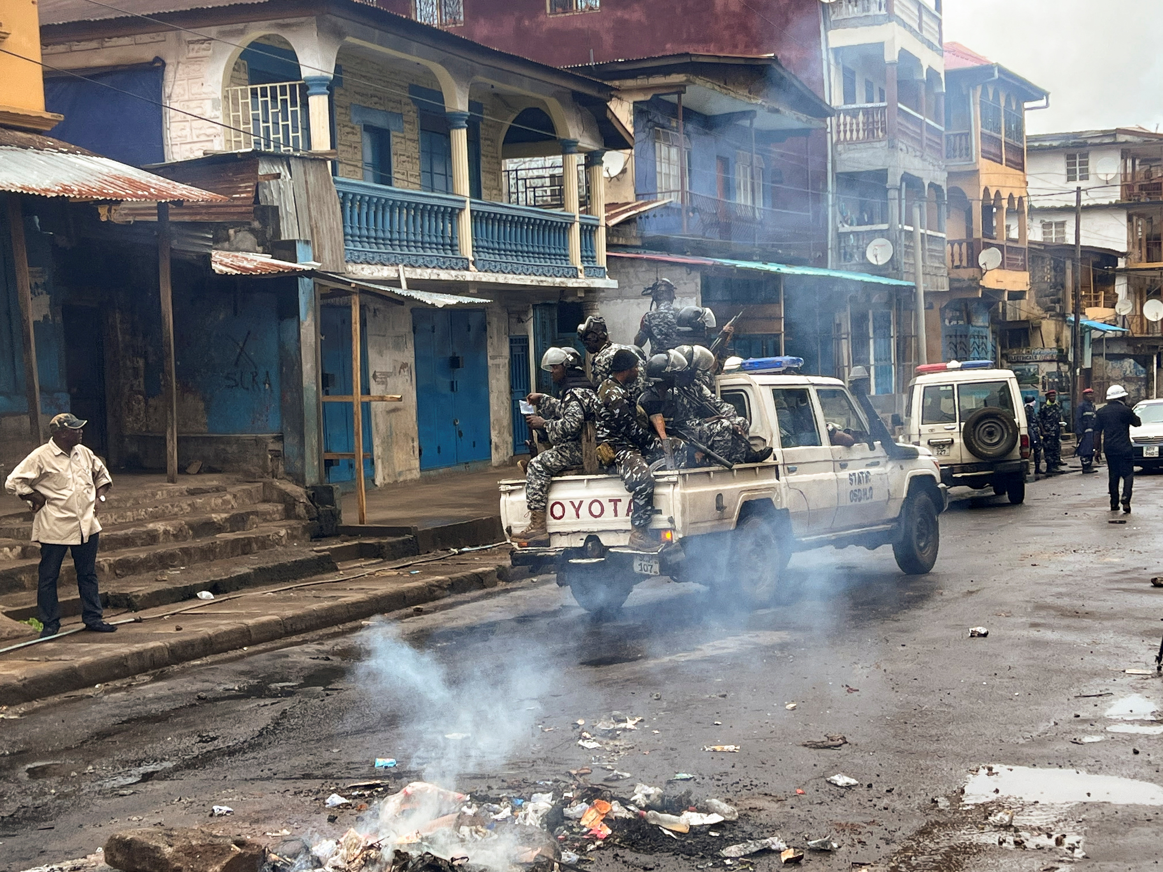 Riot police patrol as they pass smoke rising from a roadblock during anti-government protests in Freetown, Sierra Leone