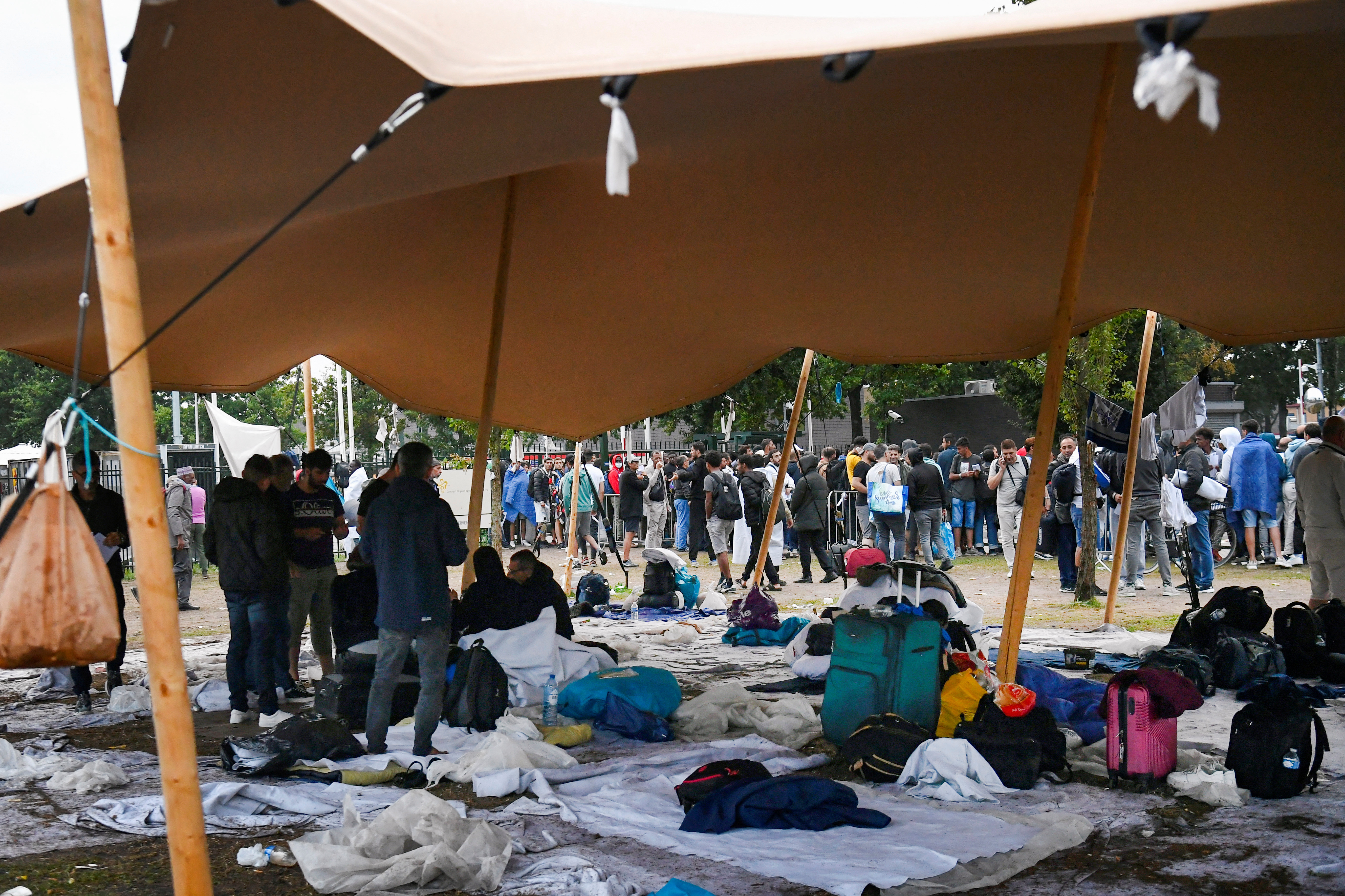 Refugees wait outdoors on the damp ground at the main reception centre for asylum seekers, in Ter Apel, Netherlands August 17, 2022. More than a hundred people have spent nights outdoors, sleeping on the roadside with little or no access to shelter or food. REUTERS/Piroschka van de Wouw