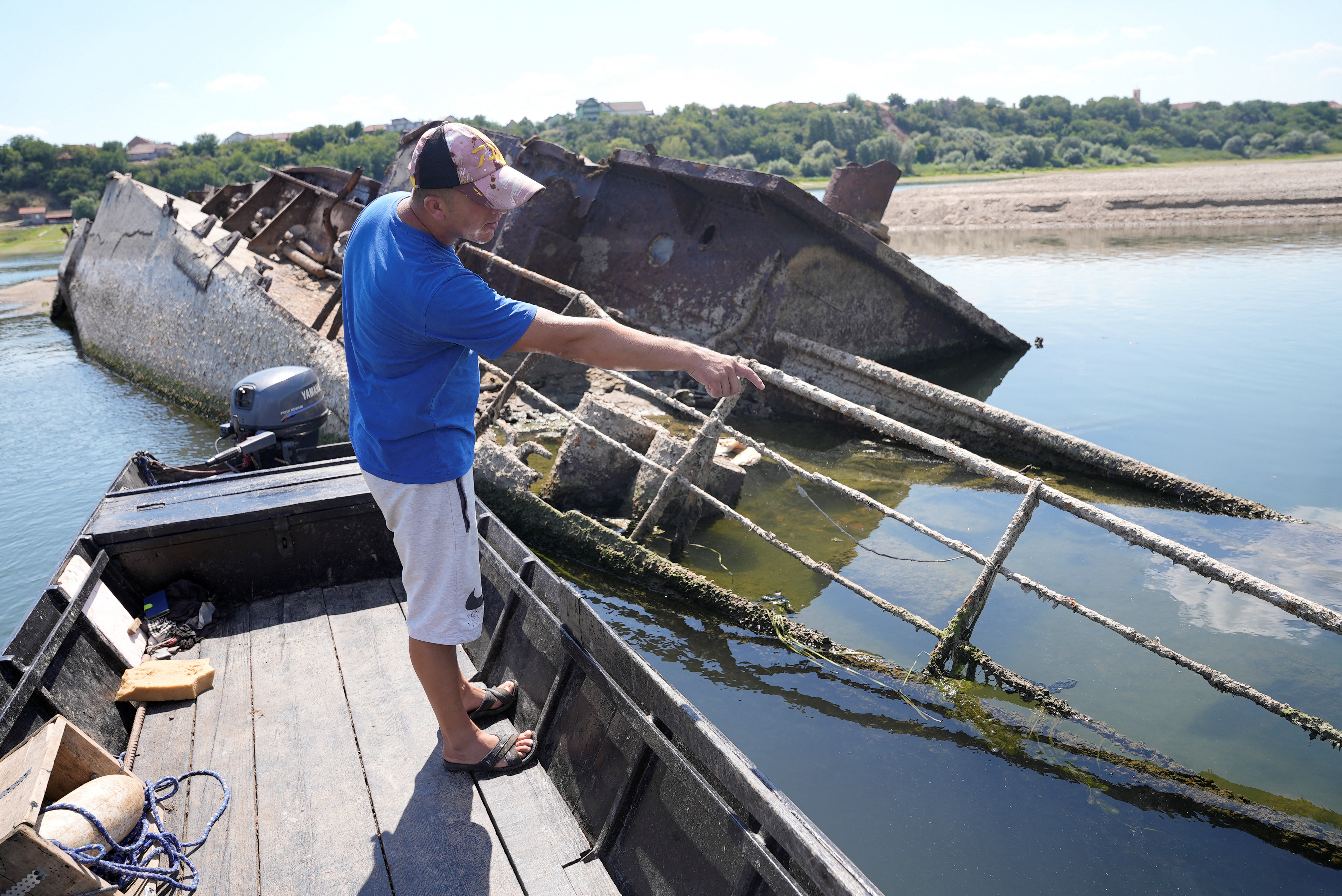 Ivica Skodric, a old local fisherman, inspects the wreckage of a German warship in the Danube in Prahovo, Serbia August on 18, 2022 [Fedja Grulovic/Reuters]