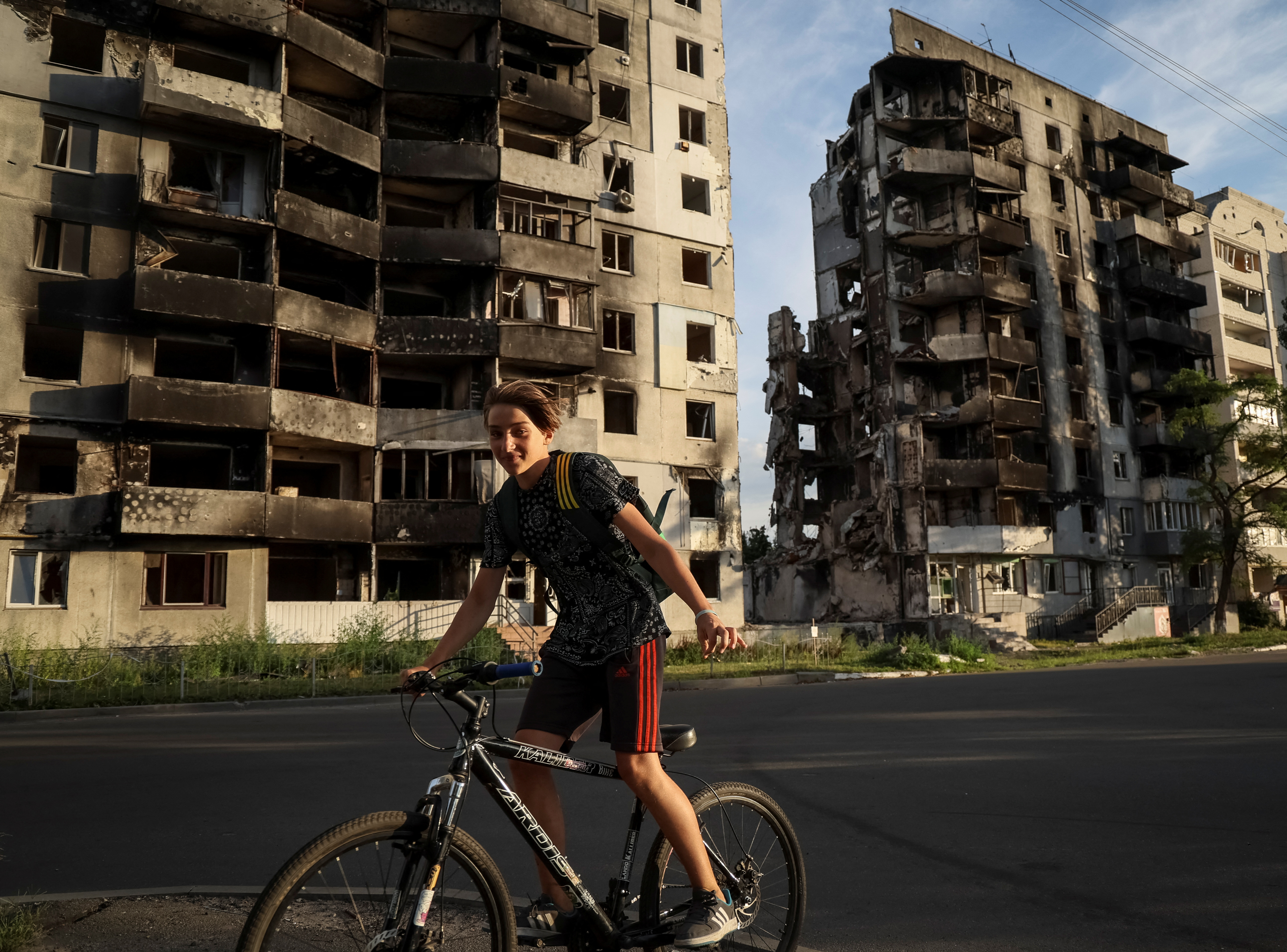 A boy rides a bike in front of destroyed buildings amid Russia's invasion of Ukraine, in the town of Borodianka, in Kyiv region, Ukraine August 26, 2022. REUTERS/Gleb Garanich