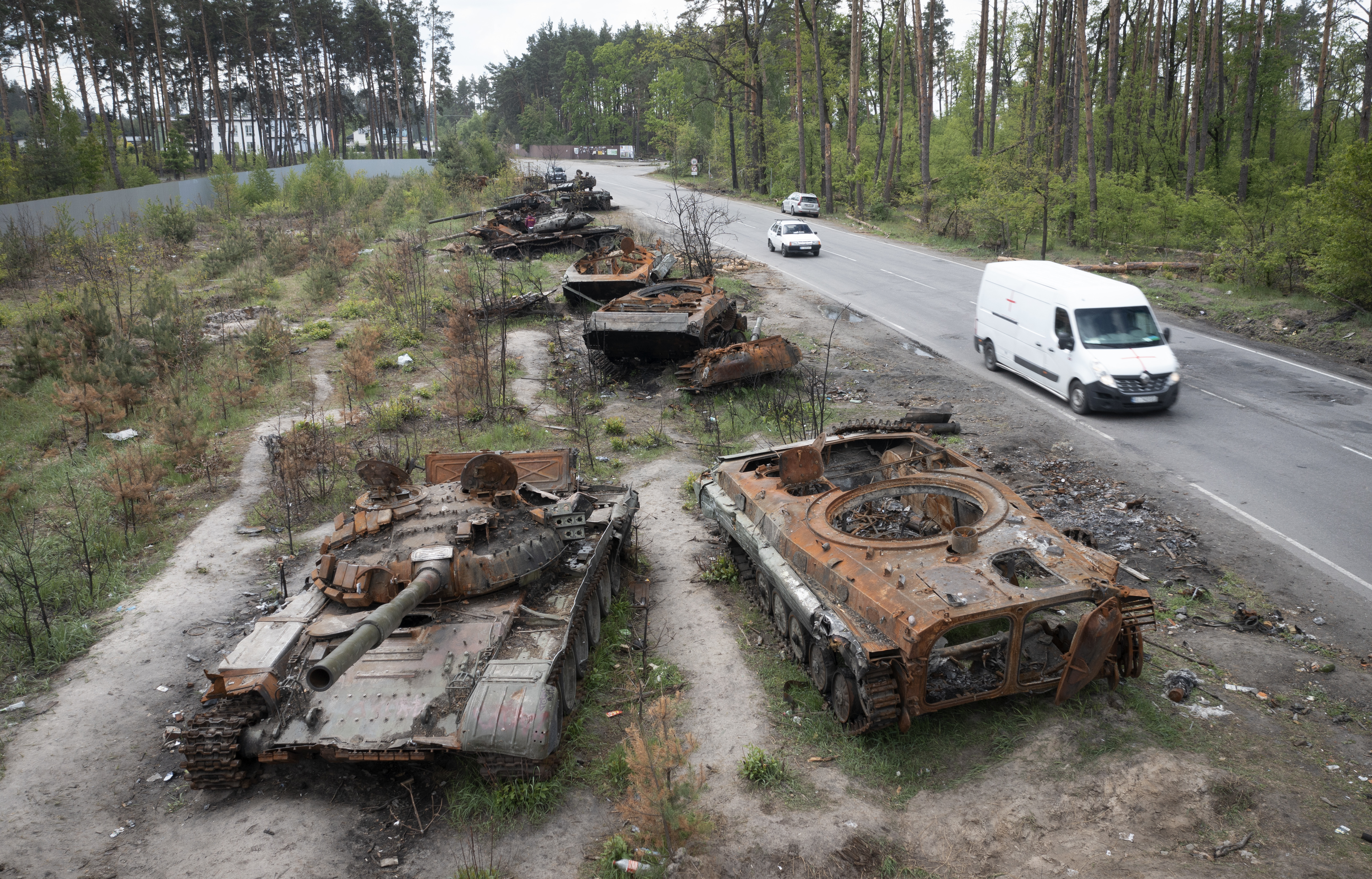 Cars pass by destroyed Russian tanks in a recent battle against Ukrainians in the village of Dmytrivka, close to Kyiv, Ukraine