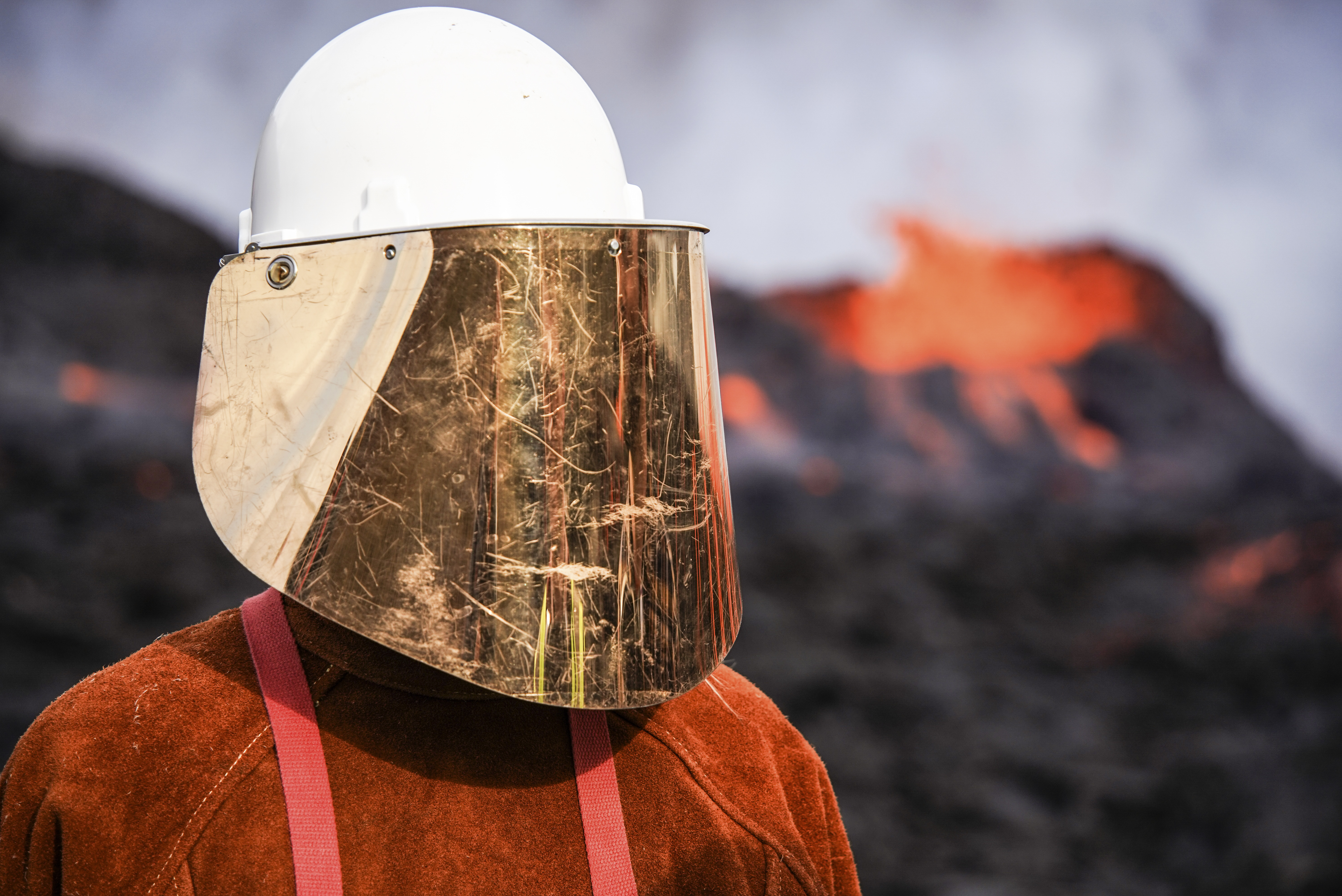 A person wears protective gear as they stand close to the lava