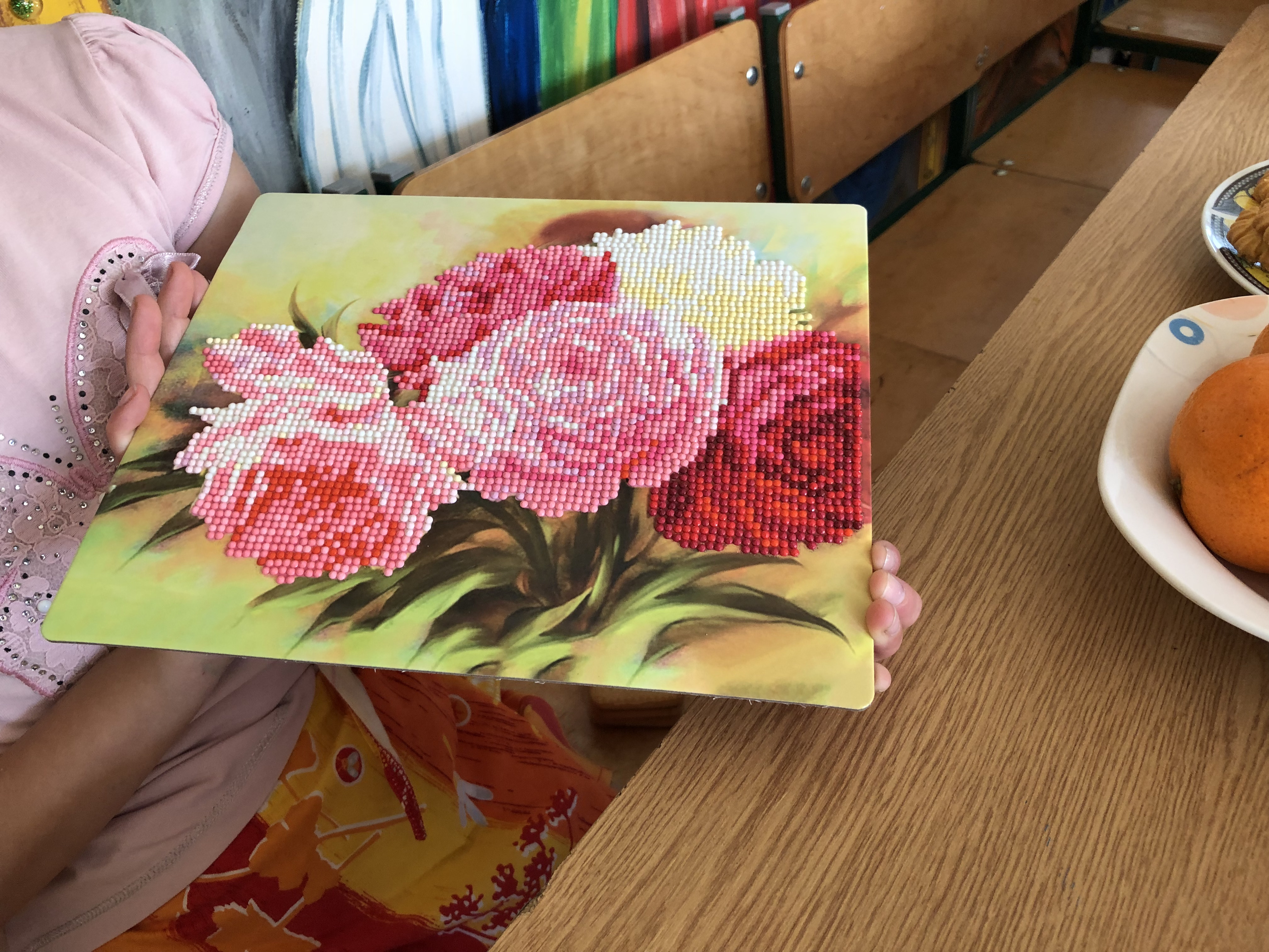 A photo of an art piece made with beads and paint.