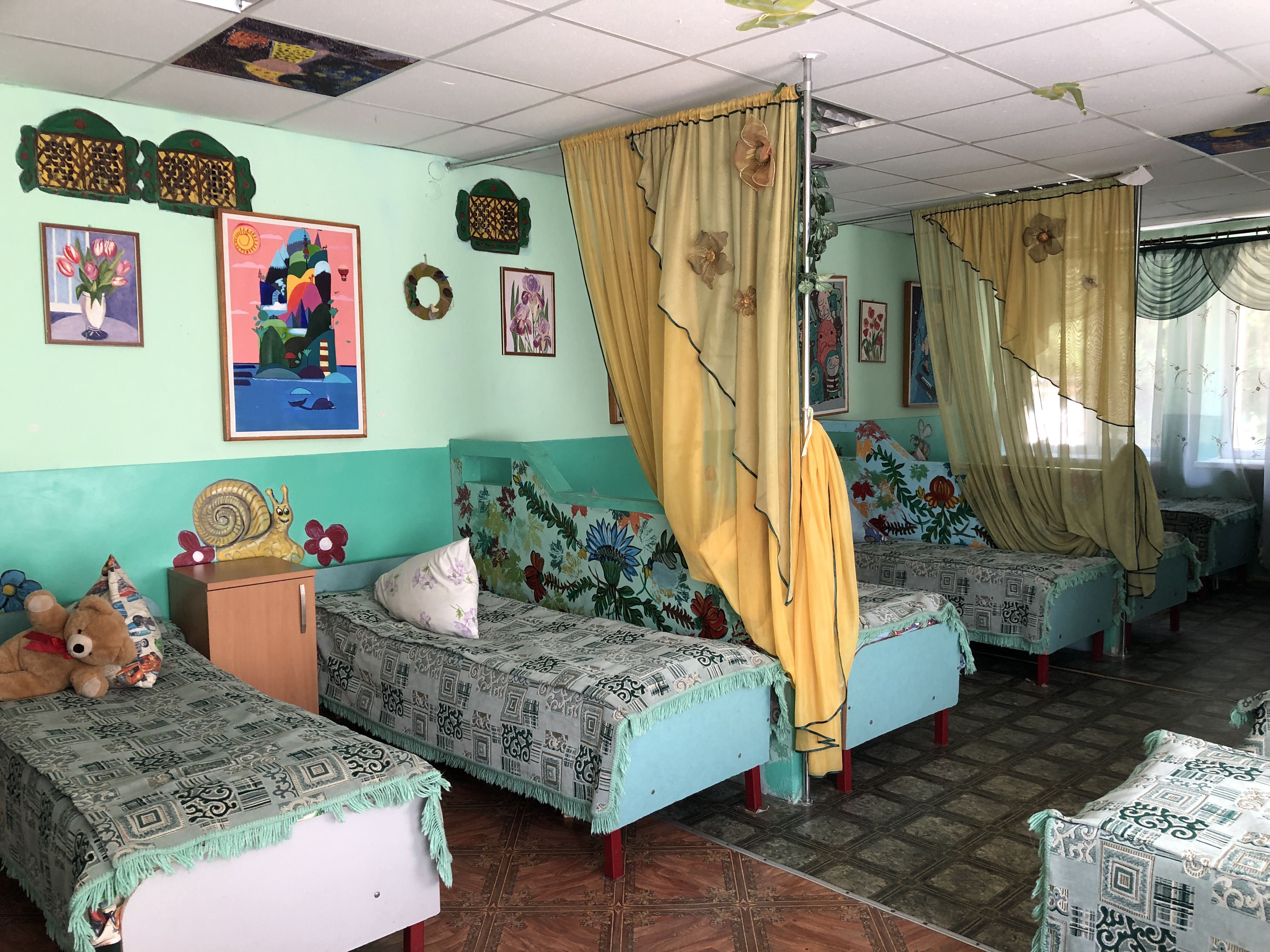 A photo of a bedroom with beds and curtains between every two beds.