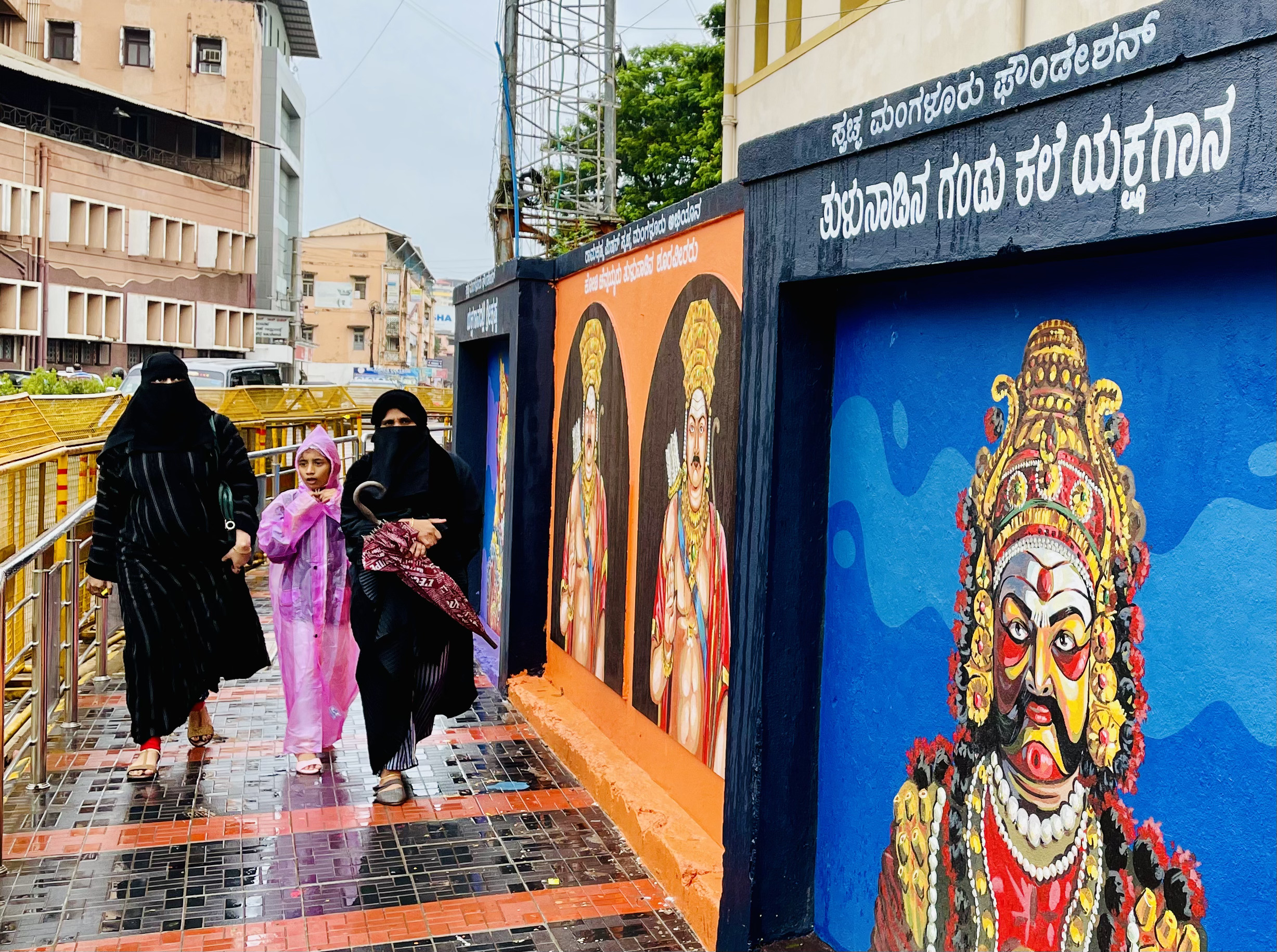 Burqa-clad women walk past graffiti of Hindu gods, which can be seen across the walls of the city.