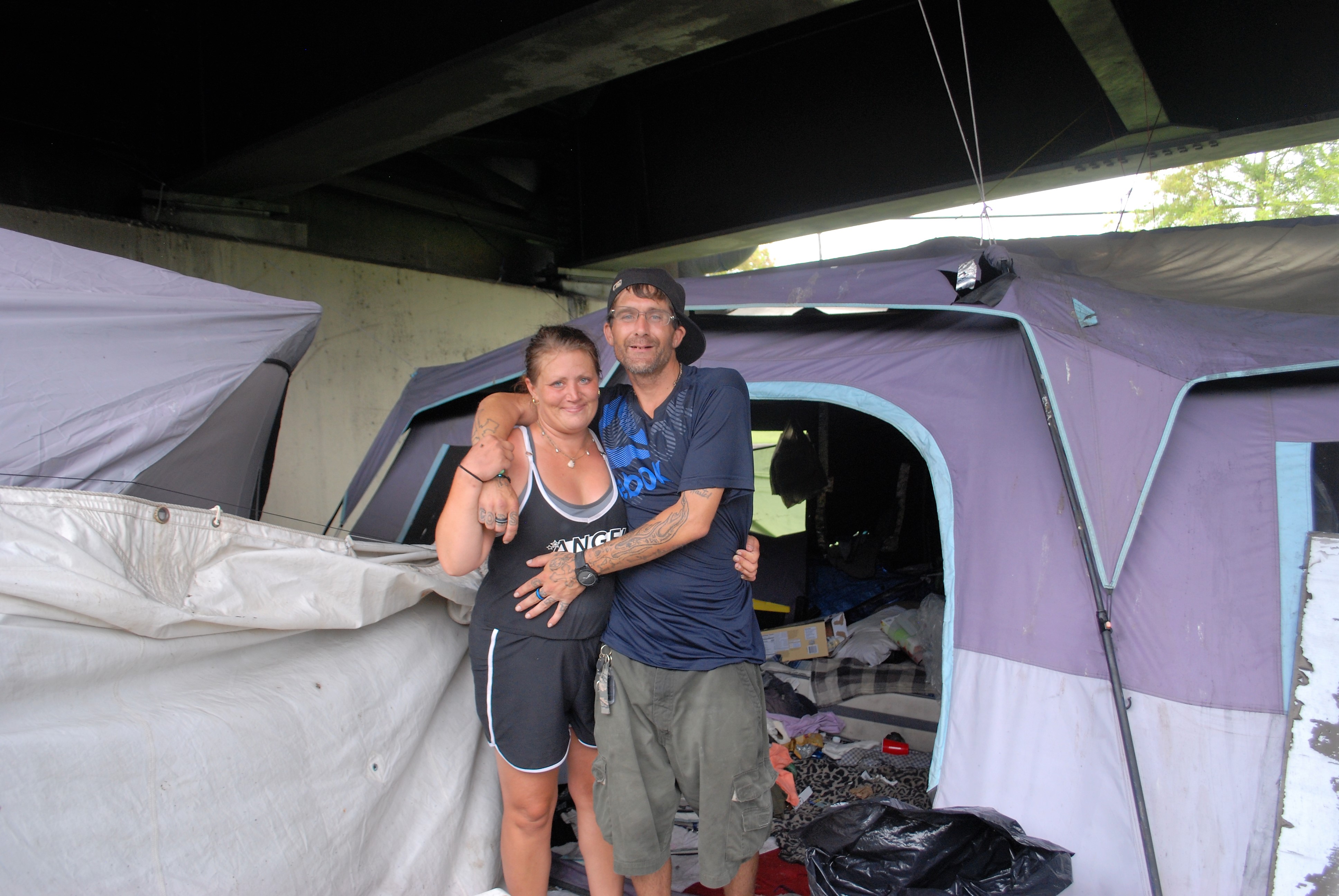 Terry and Jessica, with their arms around each other, in front of their tent.