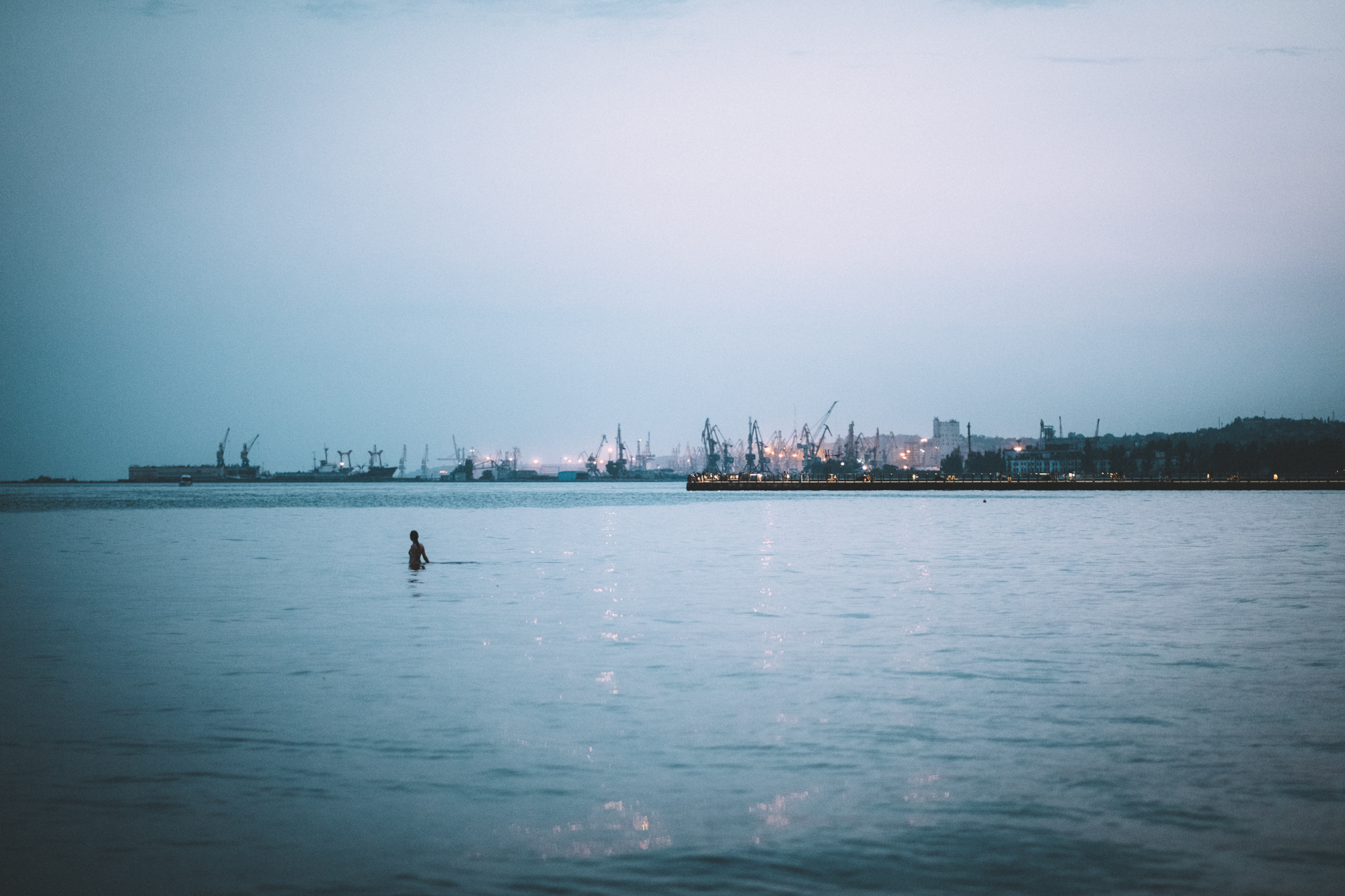 A photo of a large body of water with a person swimming in it.