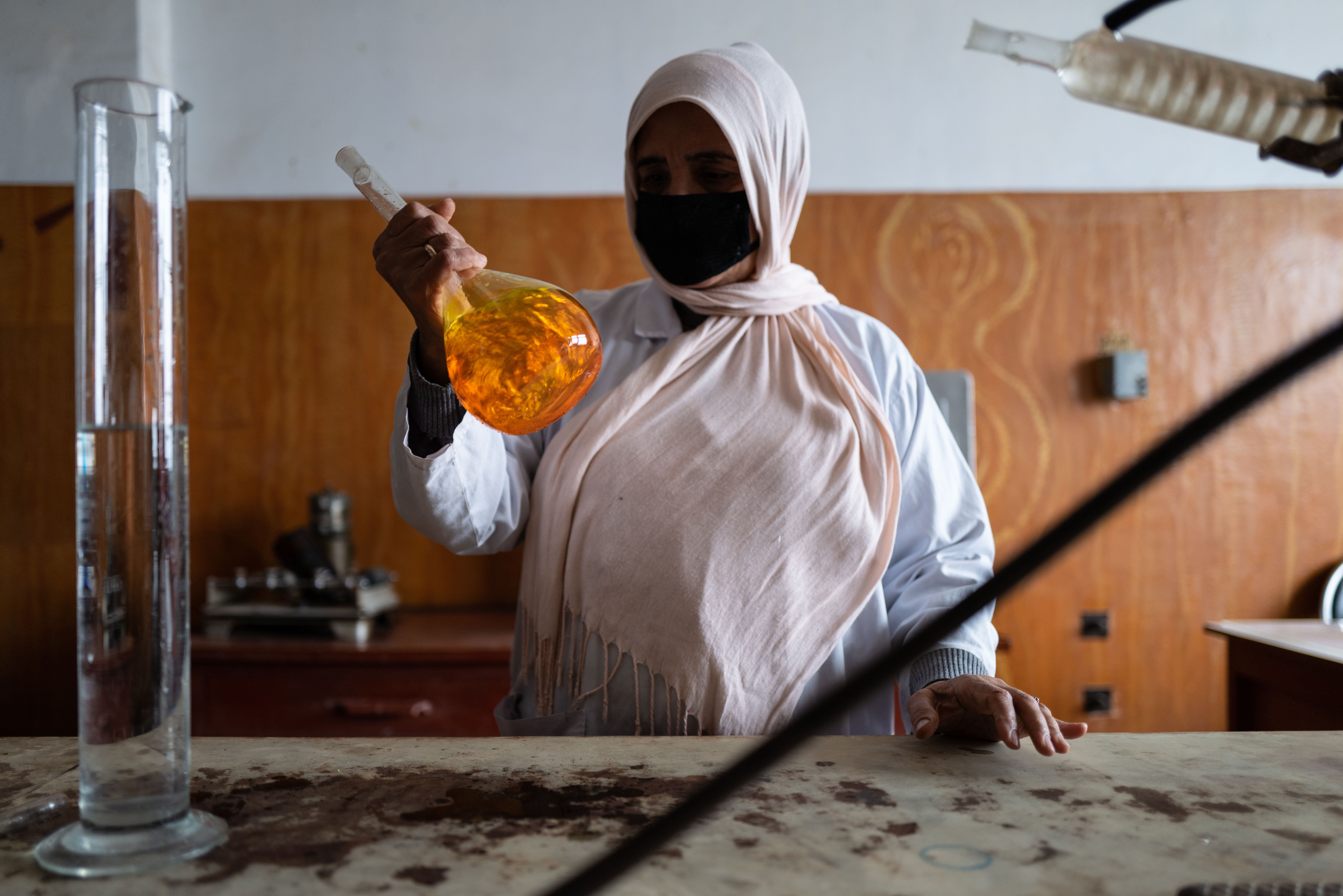 A photo of Zia Omar holding a glass filled with chemicals.