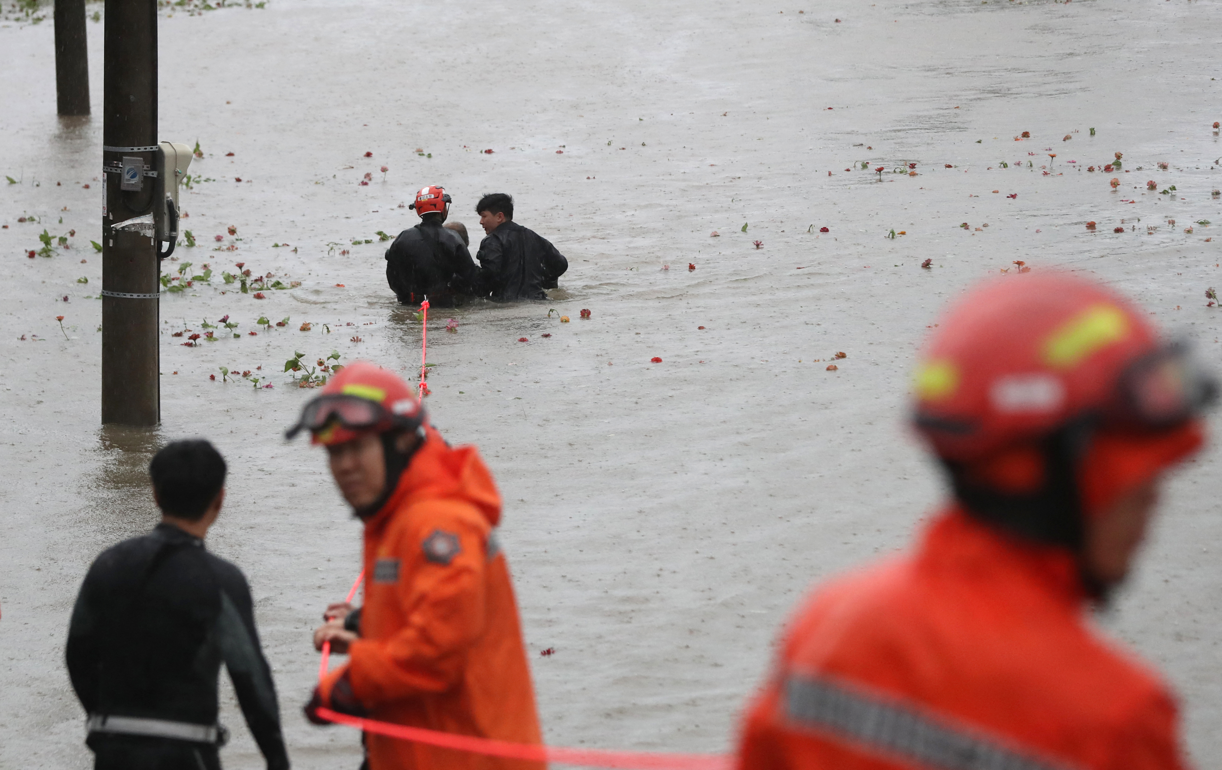 Rescue workers in orange suits rescue a man from a flooded park in Ulsan in South Korea.