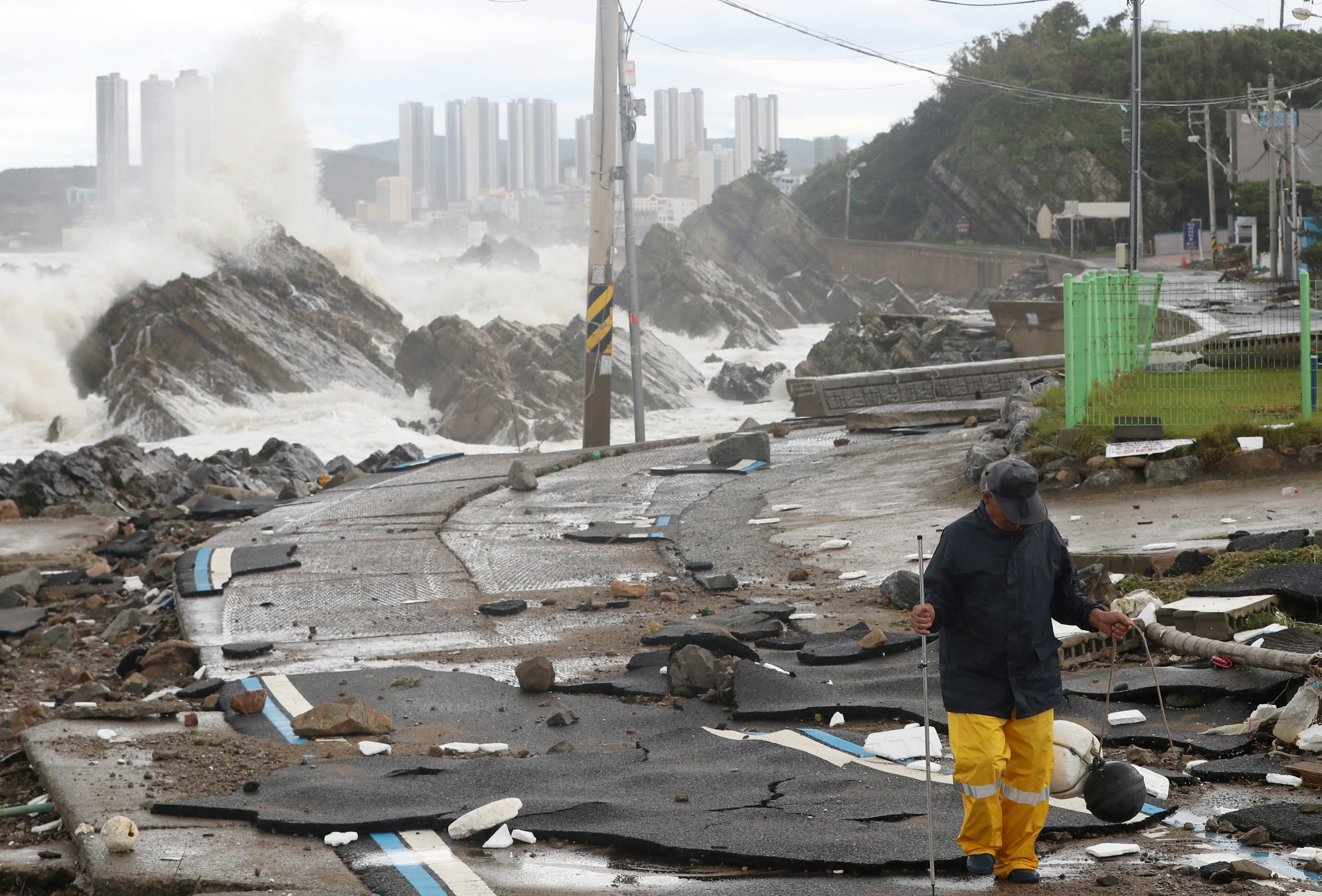 A man walks along a damaged coastal road