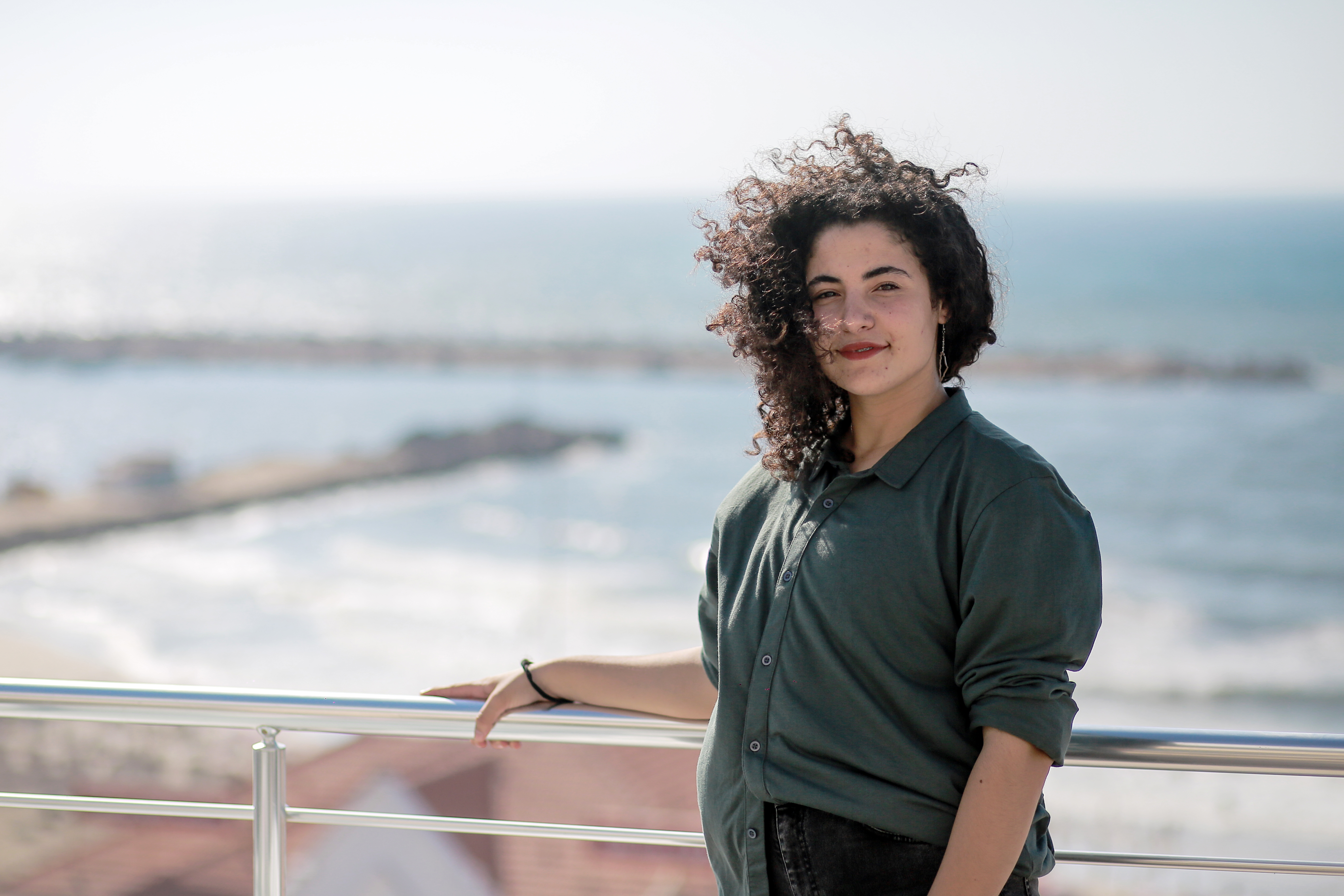 A girl stands by the sea.