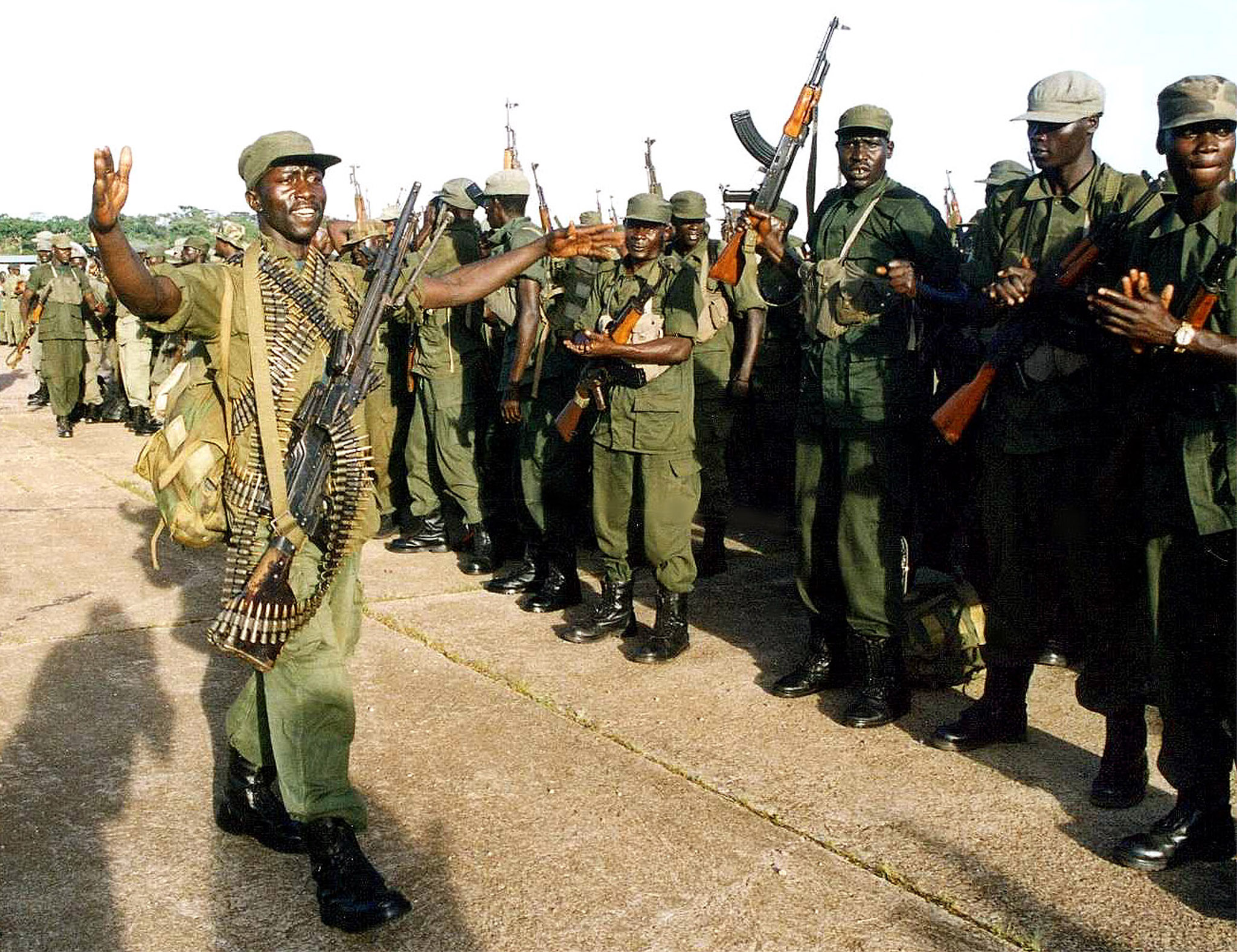 Ugandan soldiers sing and dance waving their assault rifles as they prepare to leave the eastern DR Congo town of Bunia April 25, 2003