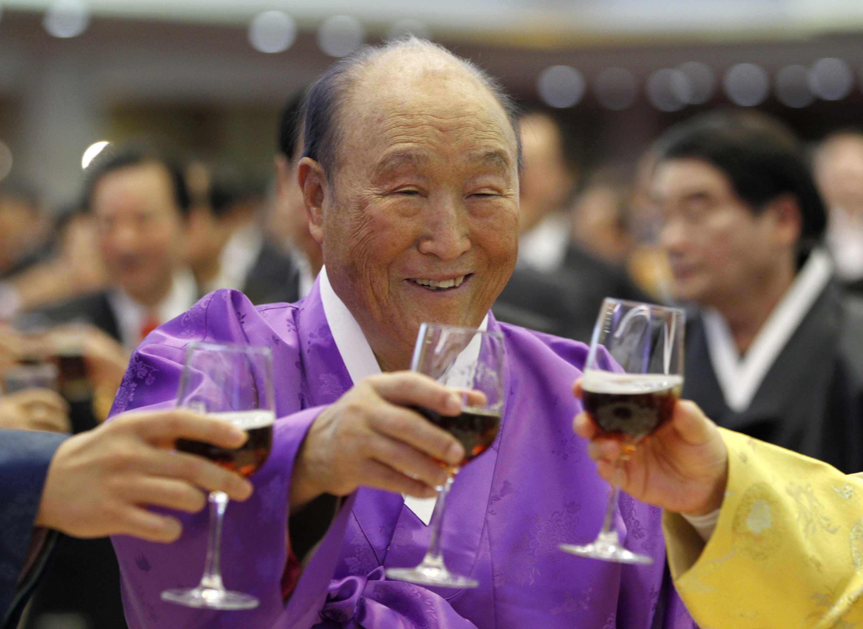 Moon Sun-myung, the founder of the Unification Church, drinks a toast with his family members during his 91st birthday party
