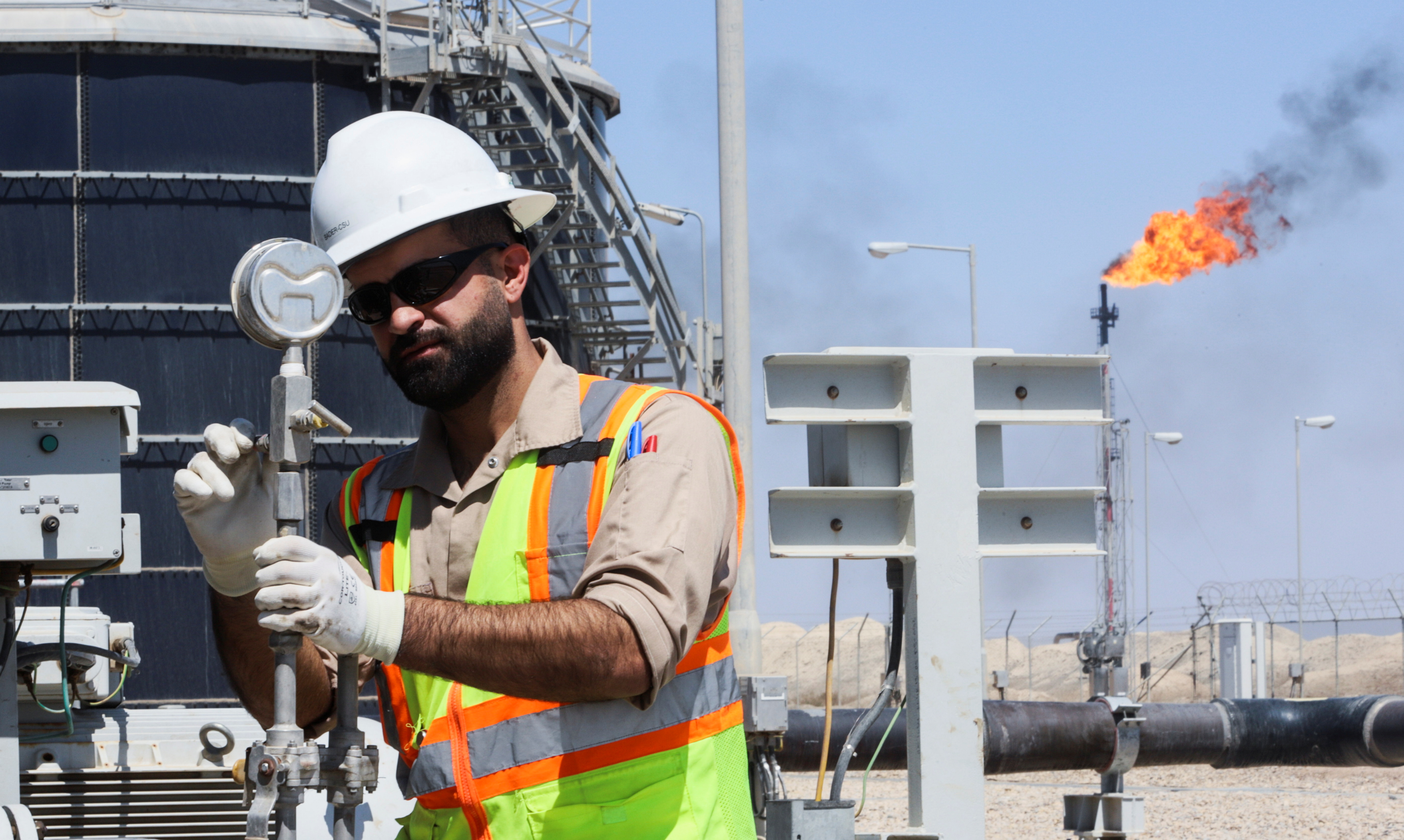A worker checks and adjusts the valve of an oil pipeline at Majnoon oil field, near Basra, Iraq, March 27, 2022.